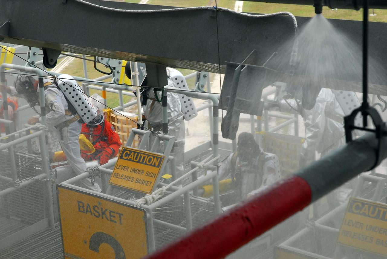 KENNEDY SPACE CENTER, FLA.  -- During a simulated rescue mission on Launch Pad 39A, known as Mode 2,  KSC workers dressed in astronauts' launch-and-entry suits climb into the slidewire baskets, helped by a fire rescue team.  The KSC rescue teams are practicing emergency procedures in the unlikely scenario of a mishap on the pad during a launch sequence.  The exercises are standard training procedures to assess and prepare emergency personnel, procedures and hardware.  Photo credit: NASA/Jack Pfaller