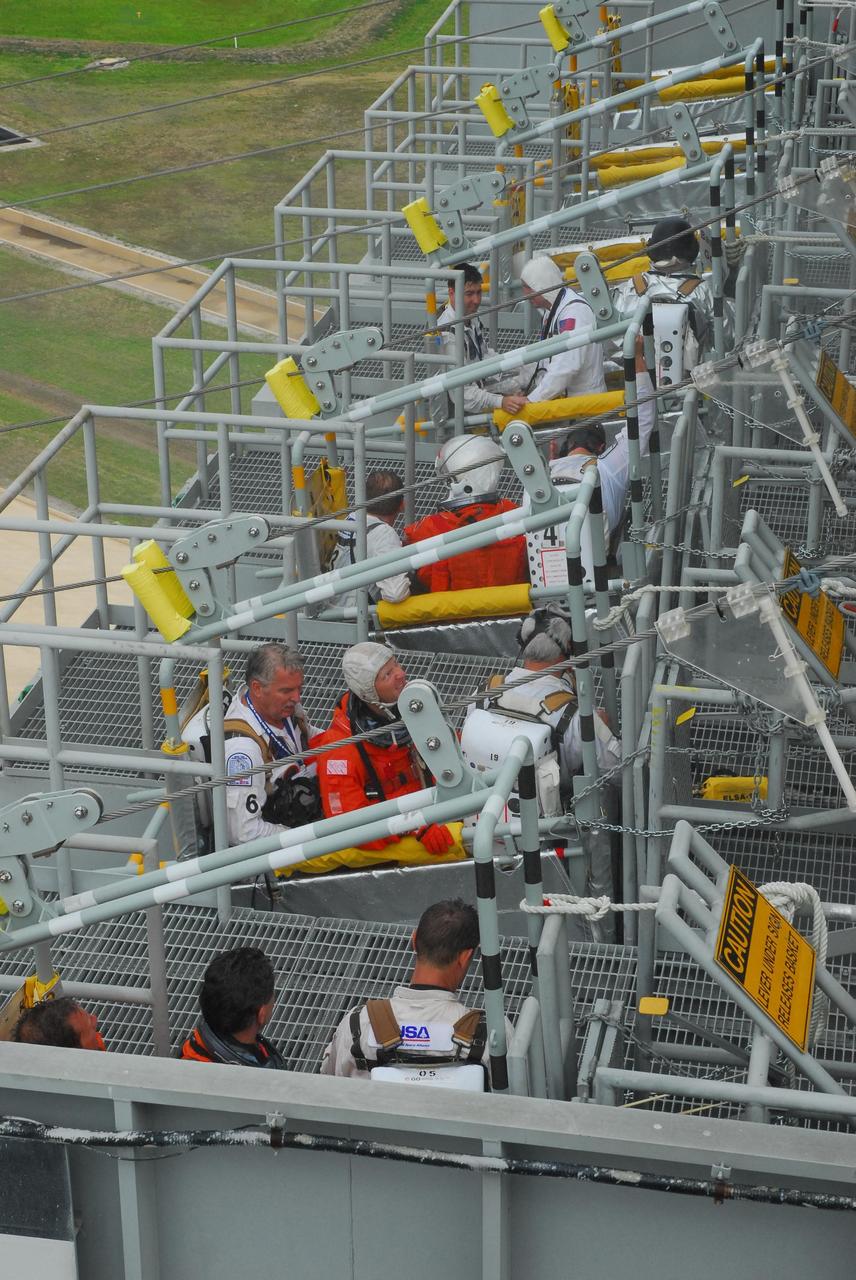 KENNEDY SPACE CENTER, FLA.  -- During a simulated rescue mission on Launch Pad 39A, known as Mode 2,  KSC workers dressed in astronauts' launch-and-entry suits are climbing into the slidewire baskets.  A fire rescue team is simulating extracting the crew from the orbiter and helping them to the baskets.The KSC rescue teams are practicing emergency procedures in the unlikely scenario of a mishap on the pad during a launch sequence.  The exercises are standard training procedures to assess and prepare emergency personnel, procedures and hardware.  Photo credit: NASA/Jack Pfaller