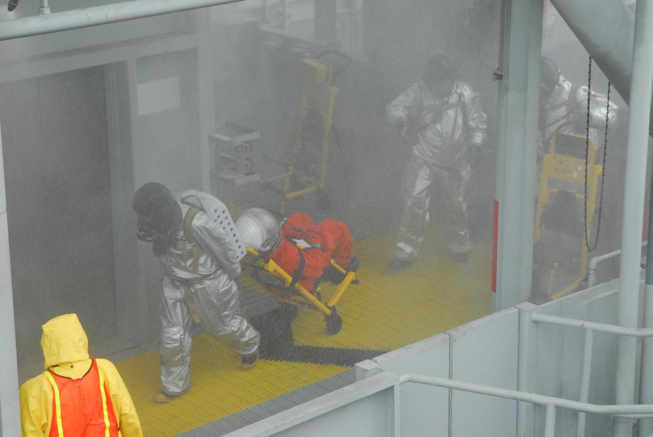 KENNEDY SPACE CENTER, FLA.  -- During a simulated rescue mission on Launch Pad 39A, known as Mode 2,  KSC workers dressed in astronauts' launch-and-entry suits are helped by the fire rescue team to the slidewire baskets on the 195-foot level. The KSC rescue teams are practicing emergency procedures in the unlikely scenario of a mishap on the pad during a launch sequence.  The exercises are standard training procedures to assess and prepare emergency personnel, procedures and hardware.  Photo credit: NASA/Jack Pfaller