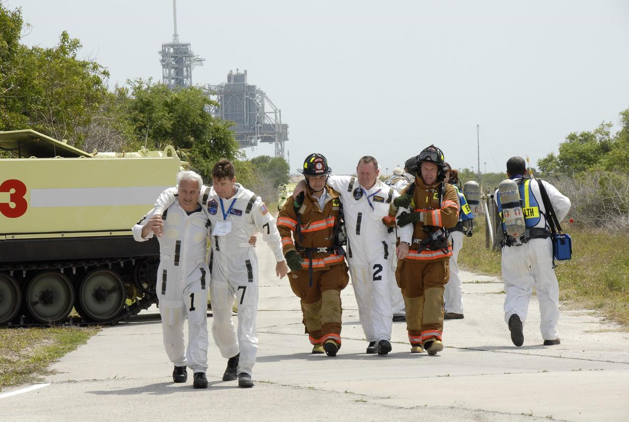 KENNEDY SPACE CENTER, FLA.  -- During the second stage of a simulated emergency, known as Mode 4,  rescue workers help KSC personnel feigning injuries to a triage area set up at Helipad 8, located near the fire station between Launch Pads 39A and 39B.  The emergency exercise began on Launch Pad 39A. The participants were helped off the pad and taken to the triage site. The "injured" workers will be airlifted to participating area hospitals. The KSC rescue teams are practicing emergency procedures in the unlikely scenario of a mishap on the pad during a launch sequence.  The exercises are standard training procedures to assess and prepare emergency personnel, procedures and hardware.  Photo credit: NASA/Kim Shiflett