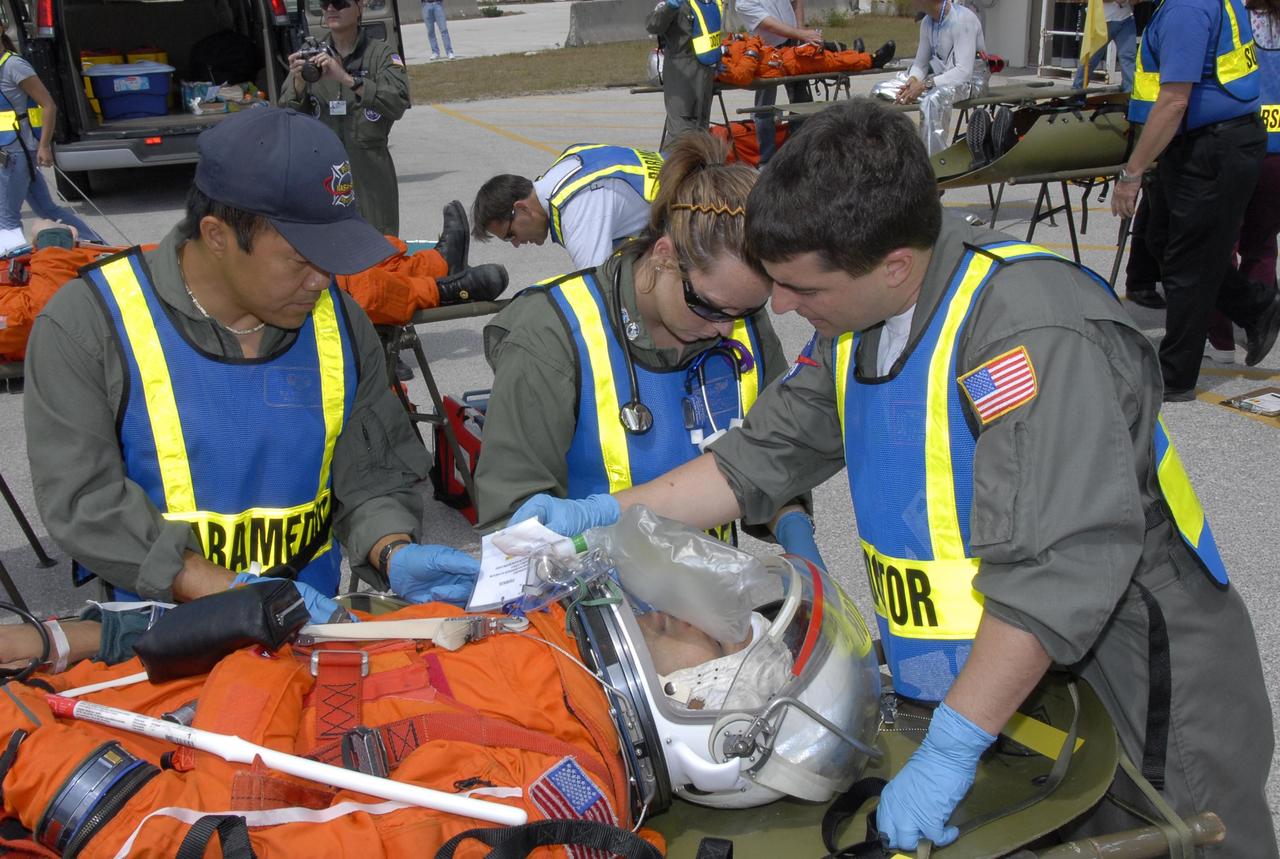 KENNEDY SPACE CENTER, FLA. -- During the second stage of a simulated emergency, known as Mode 4, a KSC rescue team helps a worker portraying an "injured" astronaut at a triage area set up at Helipad 8, located near the fire station between Launch Pads 39A and 39B. The emergency exercise began on Launch Pad 39A. The participants were helped off the pad and taken to the triage site. The "injured" worker may be airlifted to participating area hospitals. The KSC rescue teams are practicing emergency procedures in the unlikely scenario of a mishap on the pad during a launch sequence. The exercises are standard training procedures to assess and prepare emergency personnel, procedures and hardware. Photo credit: NASA/Kim Shiflett