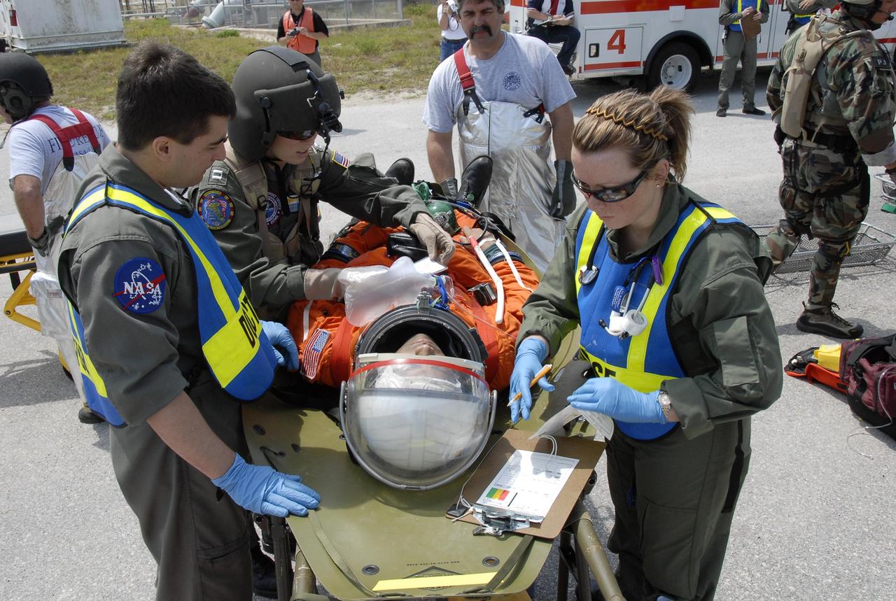 KENNEDY SPACE CENTER, FLA. -- During the second stage of a simulated emergency, known as Mode 4, the KSC rescue team monitors one of the "injured" astronauts, being portrayed by KSC personnel. The site is a triage area set up at Helipad 8, located near the fire station between Launch Pads 39A and 39B. The emergency exercise began on Launch Pad 39A. The participants were helped off the pad and taken to the triage site. The "injured" worker may be airlifted to participating area hospitals. The KSC rescue teams are practicing emergency procedures in the unlikely scenario of a mishap on the pad during a launch sequence. The exercises are standard training procedures to assess and prepare emergency personnel, procedures and hardware. Photo credit: NASA/Kim Shiflett