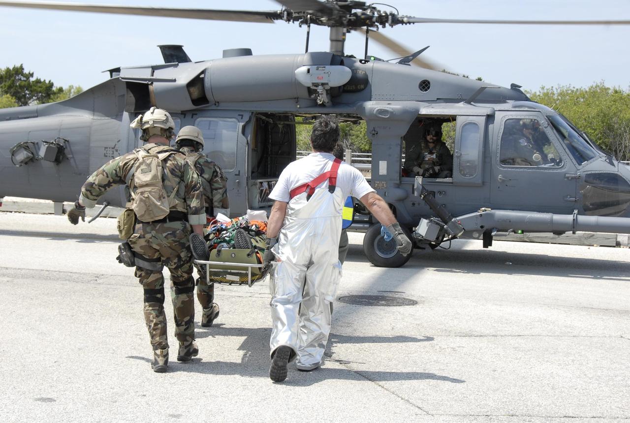 KENNEDY SPACE CENTER, FLA.  -- During the second stage of a simulated emergency, known as Mode 4, the KSC rescue team carries an "injured" astronaut toward one of five helicopters participating in the exercise.  The triage area was set up at Helipad 8, located near the fire station between Launch Pads 39A and 39B. The emergency exercise began on Launch Pad 39A. The participants were helped off the pad and taken to the triage site. The KSC rescue teams are practicing emergency procedures in the unlikely scenario of a mishap on the pad during a launch sequence.  The exercises are standard training procedures to assess and prepare emergency personnel, procedures and hardware.  Photo credit: NASA/Kim Shiflett