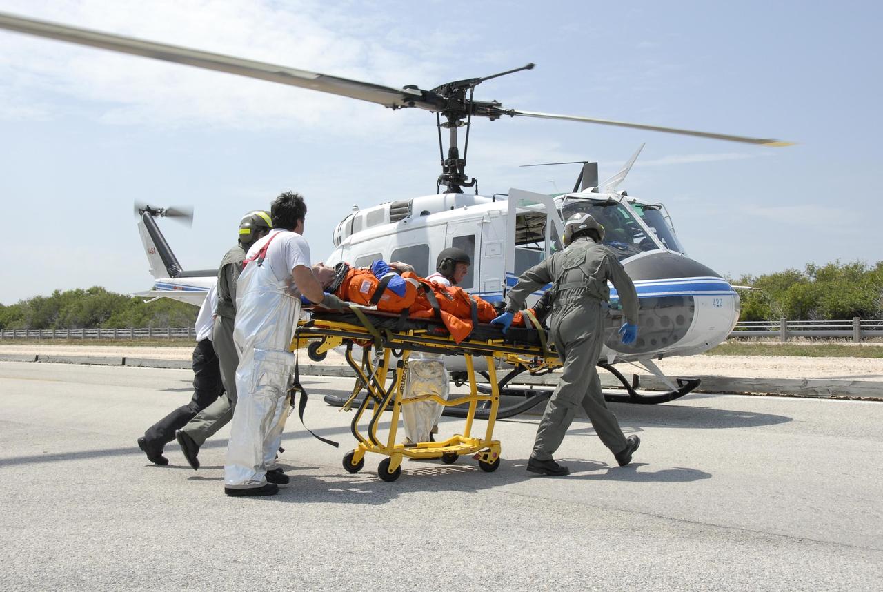 KENNEDY SPACE CENTER, FLA.  -- During the second stage of a simulated emergency, known as Mode 4, the KSC rescue team moves an "injured" astronaut toward a NASA helicopter, one of five participating in the exercise.  The triage area was set up at Helipad 8, located near the fire station between Launch Pads 39A and 39B. The emergency exercise began on Launch Pad 39A. The participants were helped off the pad and taken to the triage site. The KSC rescue teams are practicing emergency procedures in the unlikely scenario of a mishap on the pad during a launch sequence.  The exercises are standard training procedures to assess and prepare emergency personnel, procedures and hardware.  Photo credit: NASA/Kim Shiflett