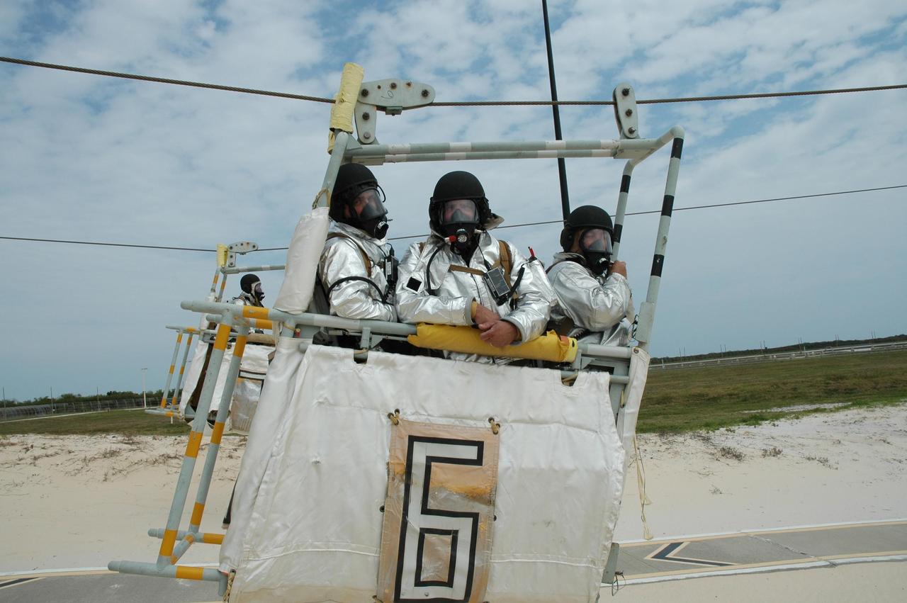KENNEDY SPACE CENTER, FLA.  -- During the second stage of a simulated emergency, known as Mode 4,  part of the KSC fire rescue team in a slidewire basket arrive at the landing site. The emergency exercise began at the 195-foot level of Launch Pad 39A. The KSC rescue teams are practicing emergency procedures in the unlikely scenario of a mishap on the pad during a launch sequence.  The exercises are standard training procedures to assess and prepare emergency personnel, procedures and hardware.  Photo credit: NASA/Jim Grossmann
