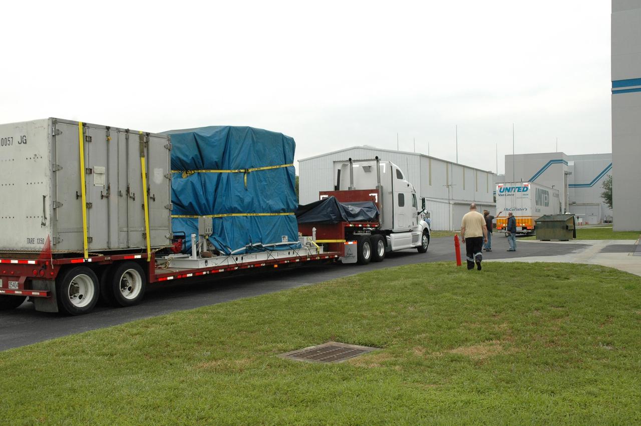KENNEDY SPACE CENTER, FLA.  -- Two trucks (one air-ride, one flat-bed) deliver the Dawn spacecraft, as well as additional electrical and ground support equipment and xenon ground support equipment, to Astrotech.  Dawn will be moved from the truck and the shipping container removed. The spacecraft will then be moved into the high bay of the Payload Processing Facility.  Dawn's mission is to explore two of the asteroid belt's most intriguing and dissimilar occupants: asteroid Vesta and the dwarf planet Ceres.  The Dawn mission is managed by JPL, a division of the California Institute of Technology in Pasadena, for NASA's Science Mission Directorate in Washington, D.C.   Photo credit: NASA/Jim Grossmann