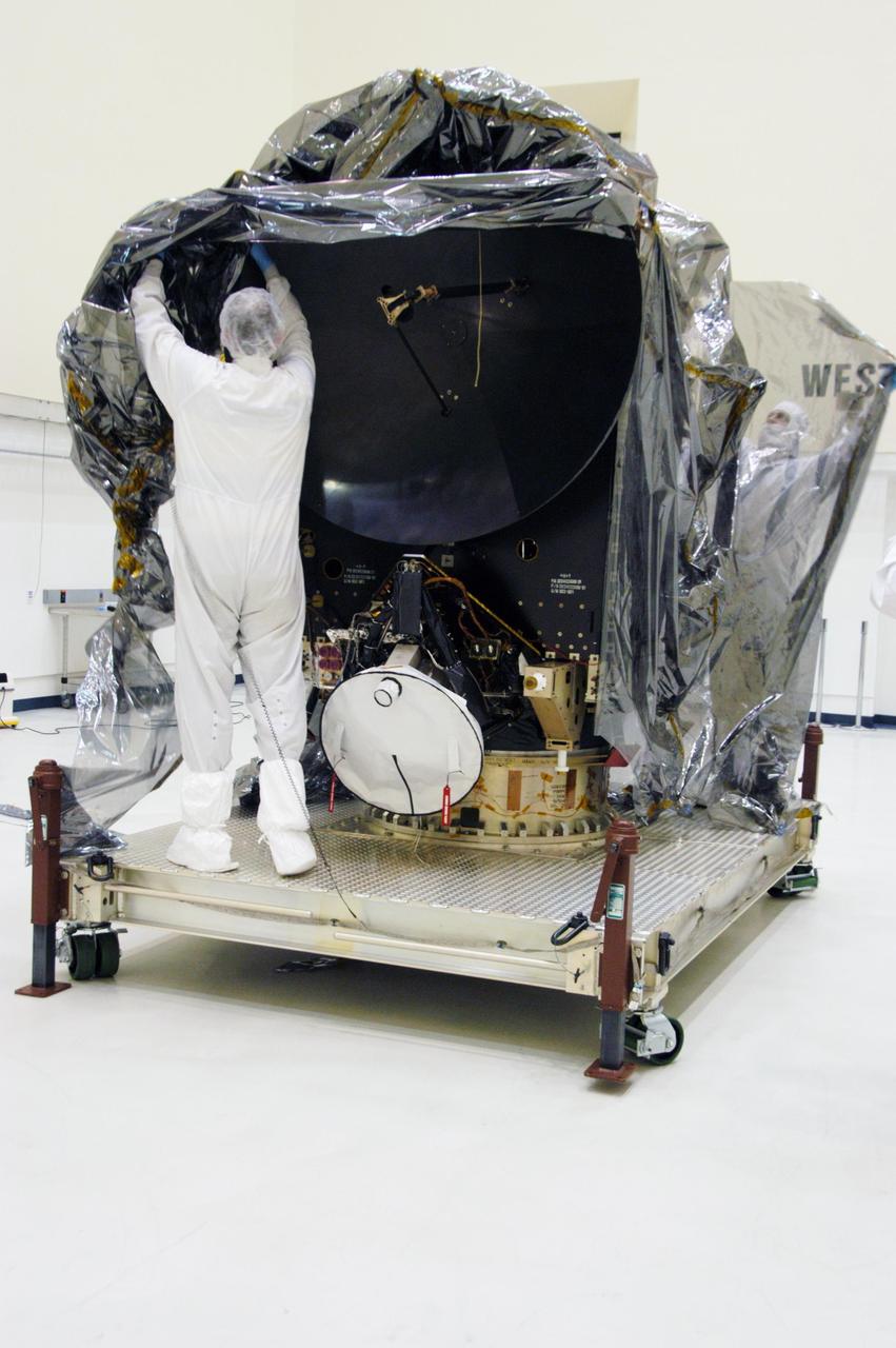 KENNEDY SPACE CENTER, FLA.  -- In clean room C of Astrotech's Payload Processing Facility, a worker wearing a "bunny suit," or clean-room attire, begins removing the protective cover surrounding the Dawn spacecraft.  In the clean room, the spacecraft will undergo further processing.  Dawn's mission is to explore two of the asteroid belt's most intriguing and dissimilar occupants: asteroid Vesta and the dwarf planet Ceres.  The Dawn mission is managed by JPL, a division of the California Institute of Technology in Pasadena, for NASA's Science Mission Directorate in Washington, D.C.   Photo credit: NASA/George Shelton