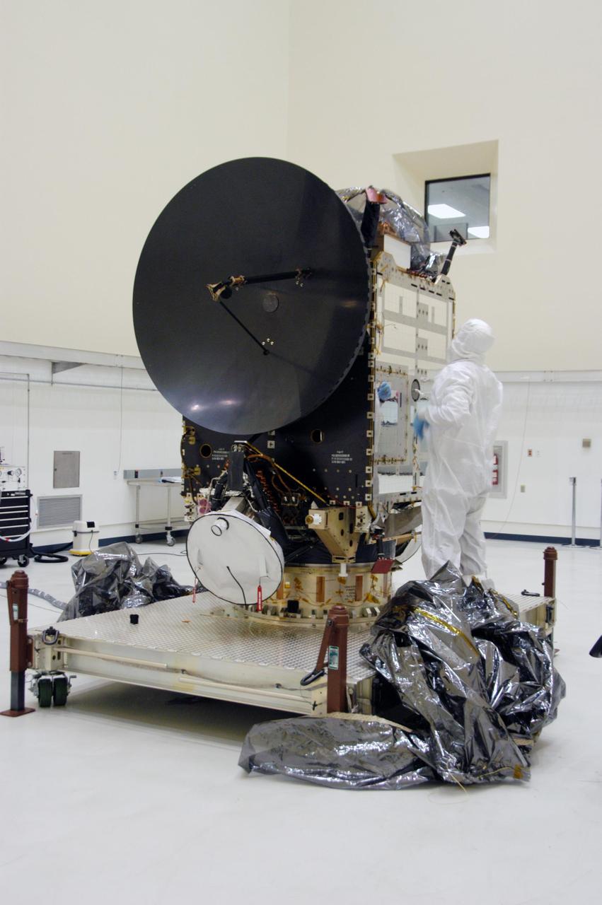 KENNEDY SPACE CENTER, FLA. -- In clean room C of Astrotech's Payload Processing Facility, a worker wearing a "bunny suit," or clean-room attire, looks over the Dawn spacecraft after removing the protective cover, at bottom right. In the clean room, the spacecraft will undergo further processing. Dawn's mission is to explore two of the asteroid belt's most intriguing and dissimilar occupants: asteroid Vesta and the dwarf planet Ceres. The Dawn mission is managed by JPL, a division of the California Institute of Technology in Pasadena, for NASA's Science Mission Directorate in Washington, D.C. Photo credit: NASA/George Shelton