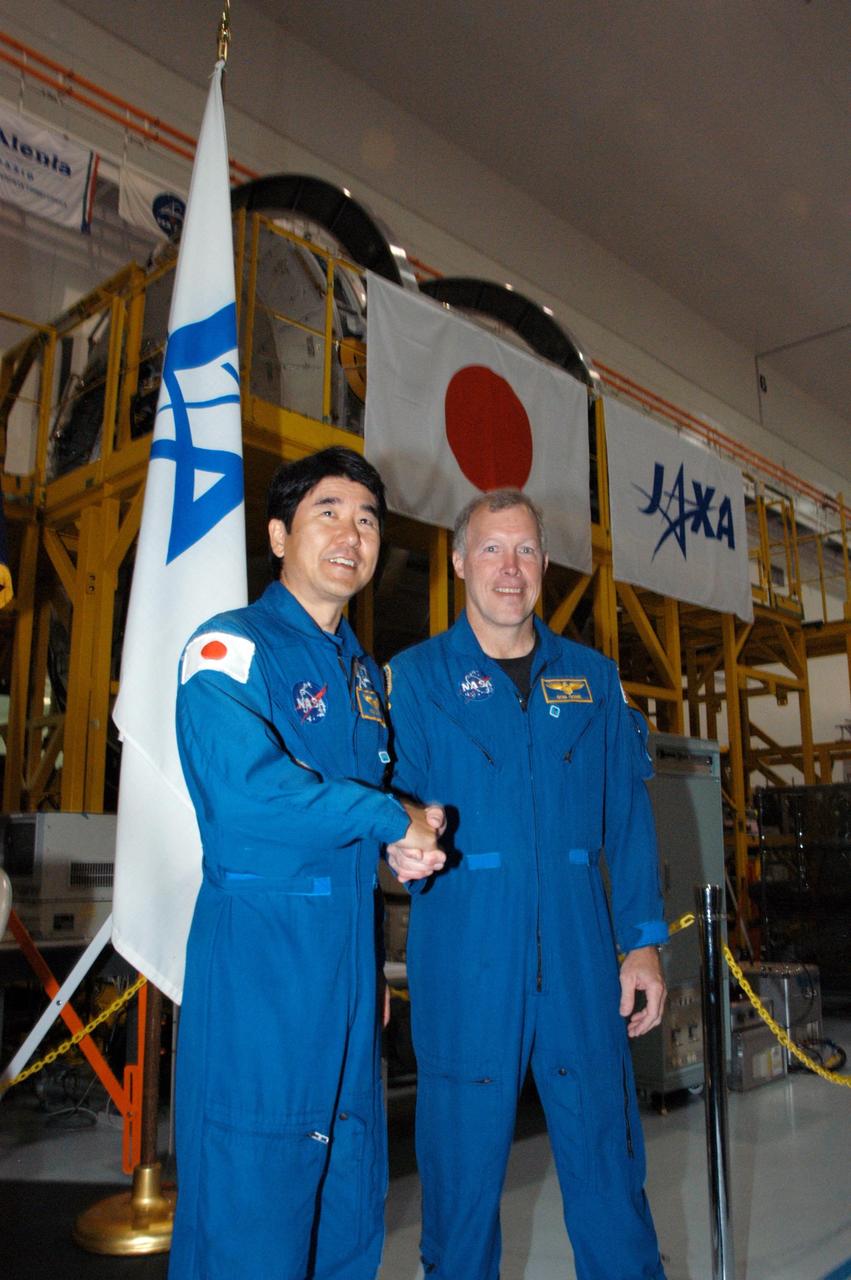 KENNEDY SPACE CENTER, FLA.  --    In the Space Station Processing Facility, astronaut Takao Doi (left) and Commander Dominic Gorie pose in front of the Experiment Logistics Module Pressurized Section for the Japanese Experiment Module, or JEM, that recently arrived at Kennedy.  Doi and Gorie are crew members for mission STS-123 that will deliver the logistics module to the International Space Station.  Earlier, NASA and Japanese Aerospace and Exploration Agency (JAXA) officials welcomed the arrival of the module.  The new International Space Station component arrived at Kennedy March 12 to begin preparations for its future launch on mission STS-123. It will serve as an on-orbit storage area for materials, tools and supplies. It can hold up to eight experiment racks and will attach to the top of another larger pressurized module.  Photo credit: NASA/George Shelton