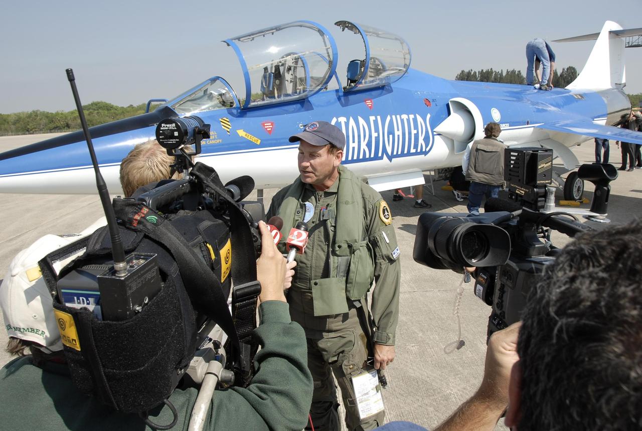 KENNEDY SPACE CENTER, FLA.  --  The media swarm around Pilot Rick Svetkoff after his test flight of the Starfighter F-104, in the background. The aircraft is taking part in a series of pathfinder test missions from the space shuttle runway. Two flights will generate test data to validate sonic boom assumptions about the potential impacts of suborbital and orbital commercial spaceflight from the facility. NASA is assessing the environmental impact of such flights.  Starfighters Inc. of Clearwater, Fla., will perform the flights to help in assessing suborbital space launch trajectories from the runway and paving the way for future commercial space tourism and research flights from the facility.  Photo credit: NASA/Kim Shiflett