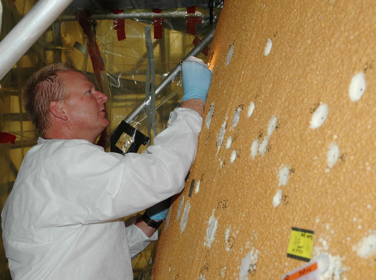 KENNEDY SPACE CENTER, FLA.  --  In the Vehicle Assembly Building, foam repairs on Atlantis' external tank include sanding and inspection, as seen here.  In late February, Atlantis' external tank received hail damage during a severe thunderstorm that passed through the Kennedy Space Center Launch Complex 39 area. The hail caused visible divots in the giant tank's foam insulation as well as minor surface damage to about 26 heat shield tiles on the shuttle's left wing.  The launch now is targeted for June 8.   Photo credit: NASA/Jack Pfaller