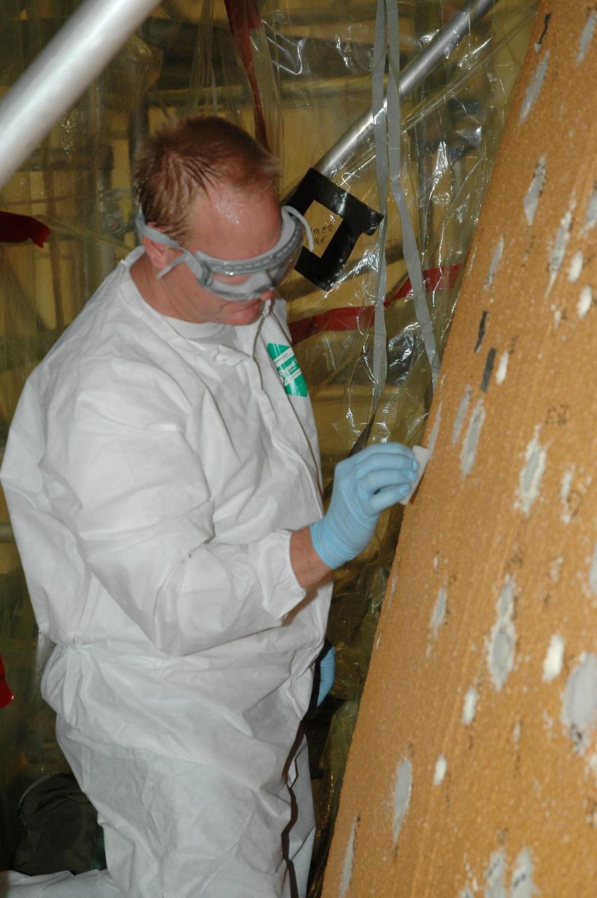 KENNEDY SPACE CENTER, FLA.  --  In the Vehicle Assembly Building, a worker carefully sands foam repairs on Atlantis' external tank.  In late February, Atlantis' external tank received hail damage during a severe thunderstorm that passed through the Kennedy Space Center Launch Complex 39 area. The hail caused visible divots in the giant tank's foam insulation as well as minor surface damage to about 26 heat shield tiles on the shuttle's left wing.  The launch now is targeted for June 8.   Photo credit: NASA/Jack Pfaller