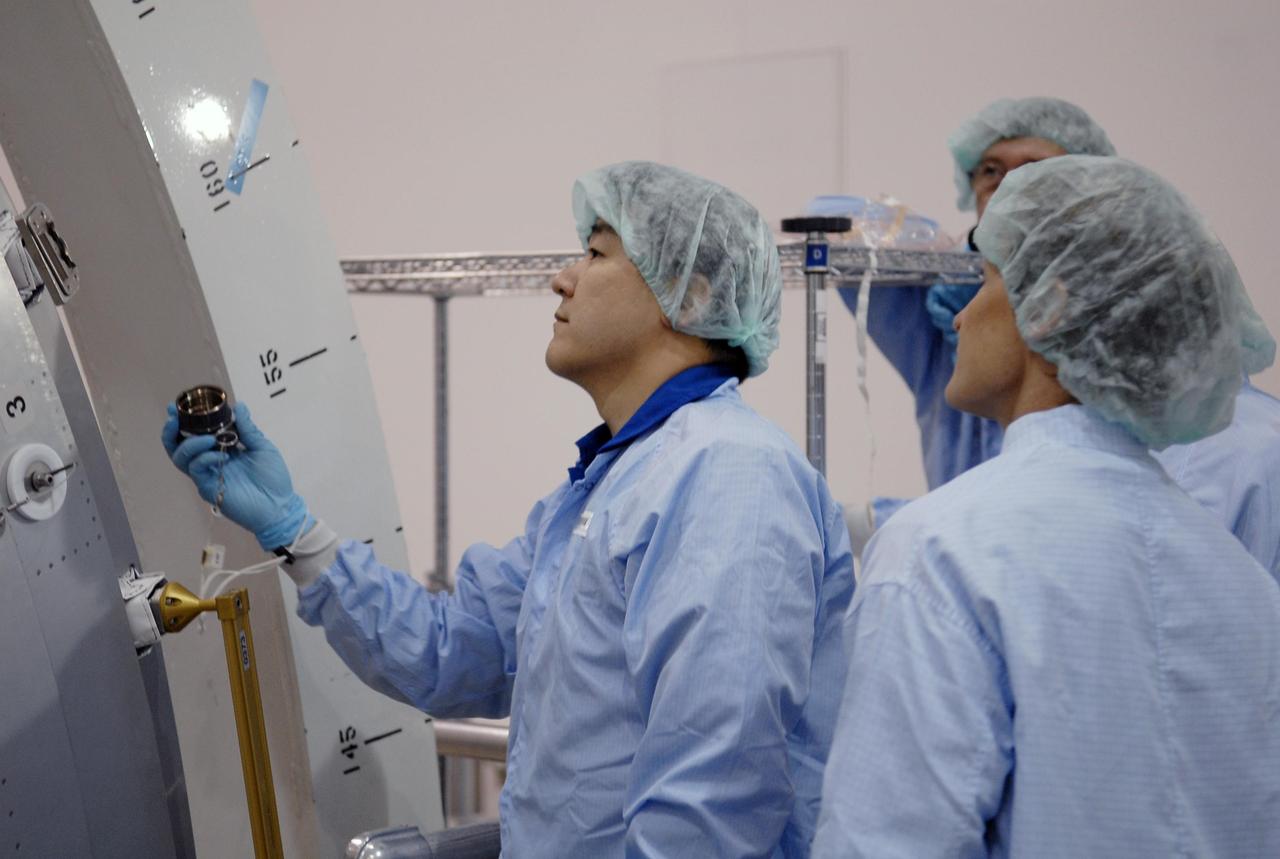 KENNEDY SPACE CENTER, FLA. -- In the Space Station Processing Facility, STS-120 Mission Specialist Daniel Tani (left) examines equipment for the Node 2, another element to be added to the International Space Station. Looking on, at right, is astronaut Peggy Whitson, who served on Expedition 5 aboard the space station. During her 6-month stay aboard the space station, Dr. Whitson installed the Mobile Base System, the S1 truss segment, and the P1 truss segment. Tani and other crew members are at KSC for equipment familiarization. Tani will be joining the Expedition 15 crew on the space station as flight engineer. Node 2 will provide a passageway between three station science experiment facilities: the U.S. Destiny Laboratory, the Kibo Japanese Experiment Module, and the European Columbus Laboratory. STS-120 is targeted for launch on October 20. Photo credit: NASA/Kim Shiflett