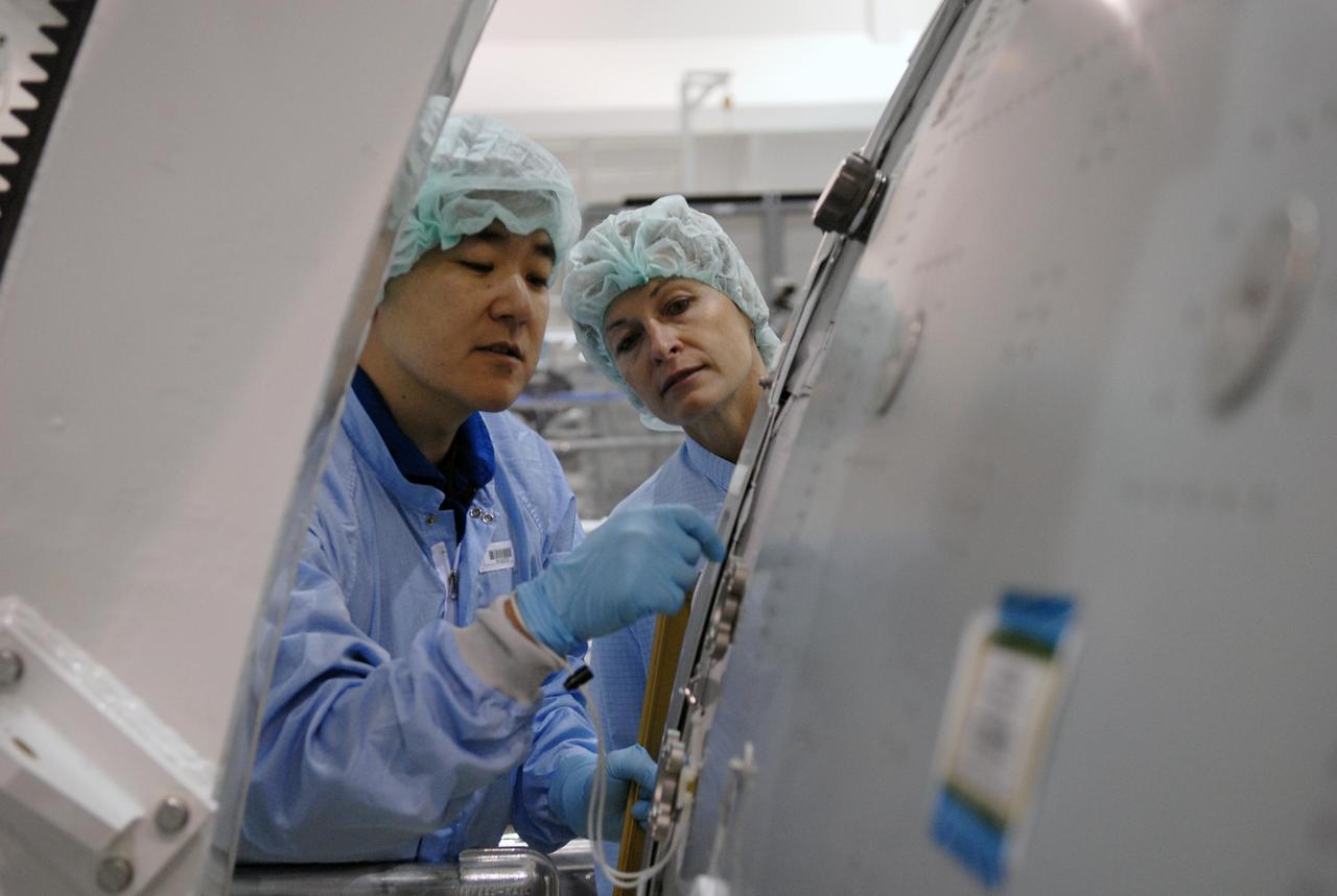 KENNEDY SPACE CENTER, FLA. -- In the Space Station Processing Facility, STS-120 Mission Specialist Daniel Tani (left) examines equipment for the Node 2, another element to be added to the International Space Station. Looking on, at right, is astronaut Peggy Whitson, who served on Expedition 5 aboard the space station. During her 6-month stay aboard the space station, Dr. Whitson installed the Mobile Base System, the S1 truss segment, and the P1 truss segment. Tani and other crew members are at KSC for equipment familiarization. Tani will be joining the Expedition 15 crew on the space station as flight engineer. Node 2 will provide a passageway between three station science experiment facilities: the U.S. Destiny Laboratory, the Kibo Japanese Experiment Module, and the European Columbus Laboratory. STS-120 is targeted for launch on October 20. Photo credit: NASA/Kim Shiflett