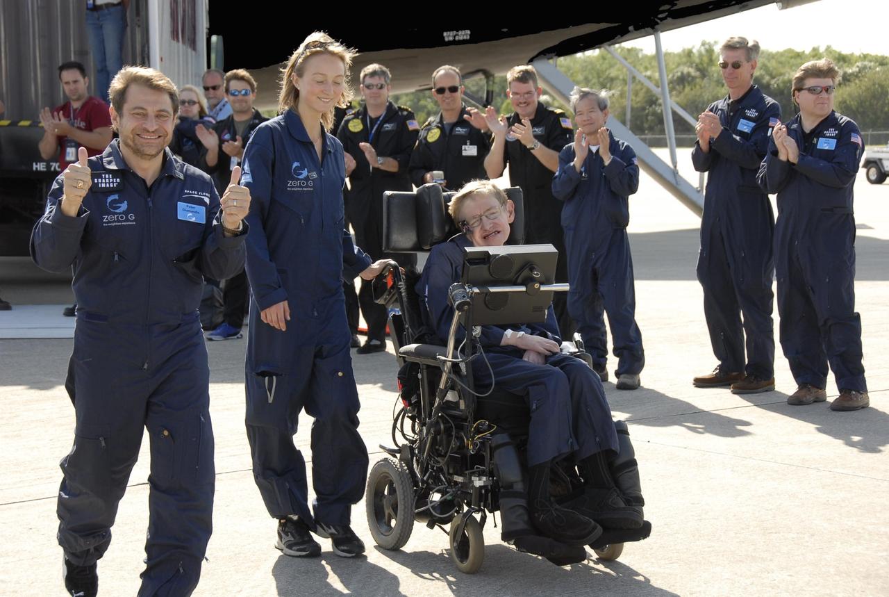 KENNEDY SPACE CENTER, FLA. -- Well-wishers greet noted physicist Stephen Hawking (in the wheelchair) at the Kennedy Space Center Shuttle Landing Facility after a zero gravity flight.  Next to him at left are Peter Diamandis, founder of the Zero Gravity Corp. that provided the flight aboard its modified Boeing 727, and Nicola O'Brien, a nurse practitioner who is Hawking's aide. Hawking suffers from amyotrophic lateral sclerosis (also known as Lou Gehrig's disease).  At the celebration of his 65th birthday on January 8 this year, Hawking announced his plans for a zero-gravity flight to prepare for a sub-orbital space flight in 2009 on Virgin Galactic's space service.  Photo credit: NASA/Kim Shiflett