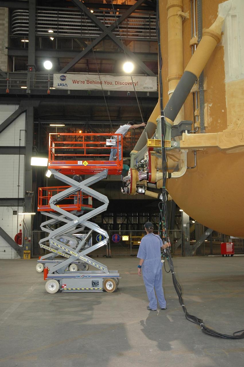 KENNEDY SPACE CENTER, FLA. -- In the Vehicle Assembly Building, a worker checks the cable attached from the framework around external tank No. 117 to the overhead crane. The tank is suspended vertically above the transfer aisle before being lifted into the checkout cell in high bay 2 for processing. ET-117 arrived aboard the Pegasus barge after its voyage around the Florida Peninsula from the Michoud Assembly Facility near New Orleans. The tank is slated for mission STS-118, which is targeted for launch in early August. Photo credit: NASA/Jack Pfaller