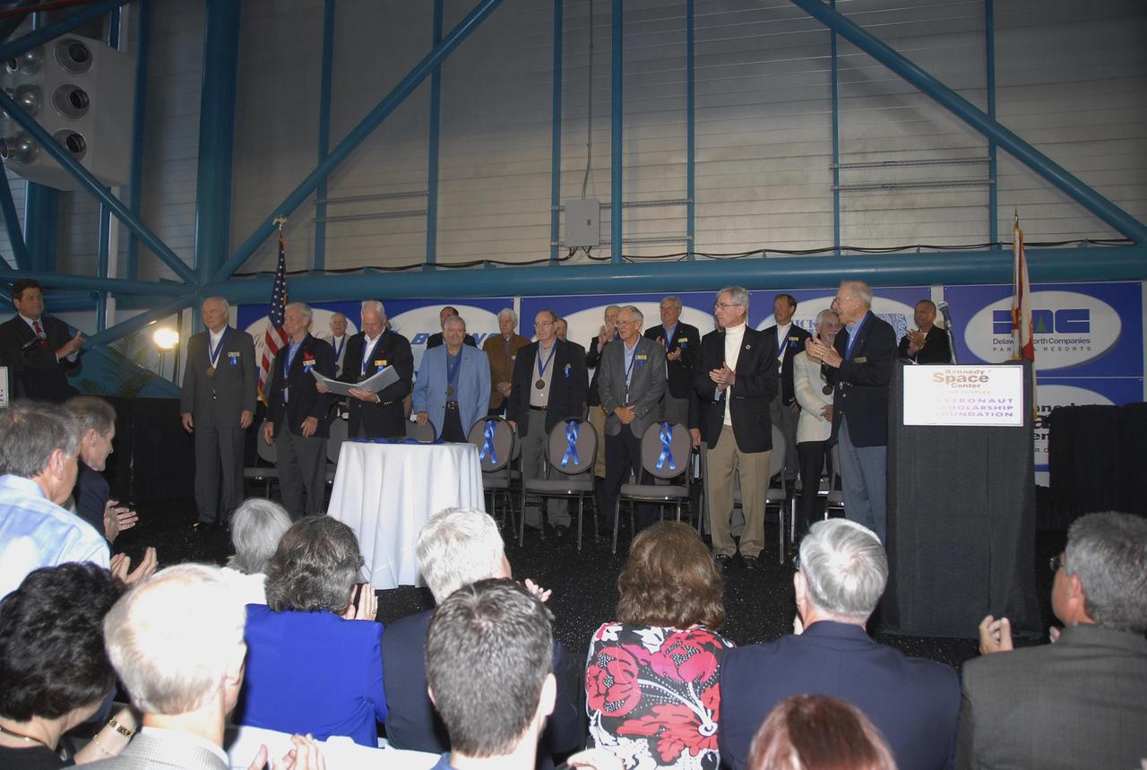 KENNEDY SPACE CENTER, FLA. --    Retired Astronaut Al Worden (third from left in front row) reads a list of the astronauts honored in past ceremonies, some of whom stand on the dais. Standing in the front row, from left, are John Glenn, Scott Carpenter, Worden, Fred Haise, Edgar Mitchell, Charlie Duke, John Young and Jim Lovell. Pictured standing in the back row, from left, are Jerry Carr, Bob Crippen, Hank Hartsfield, Joe Allen, Rick Hauck, Dan Brandenstein, Robert “Hoot” Gibson, Owen Garriott and Charlie Bolden. The May 5 induction added space shuttle commanders Michael L. Coats, Steven A. Hawley and Jeffrey A. Hoffman to the Hall of Fame.  They grow the number of space explorers enshrined in the Hall of Fame to 66. The ceremony was held at the Kennedy Space Center's Apollo/Saturn V Center.  Photo credit: NASA/Kim Shiflett