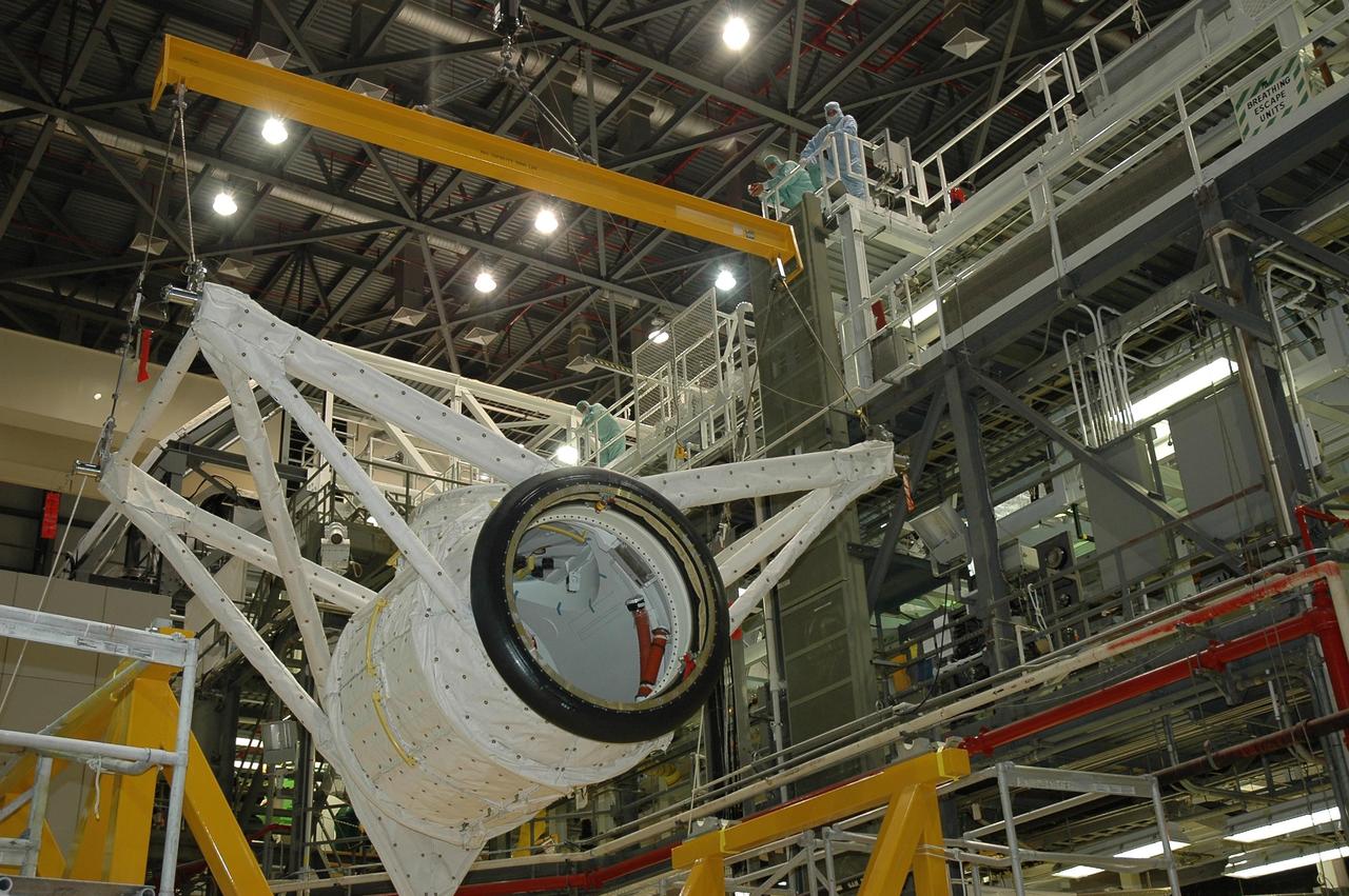 KENNEDY SPACE CENTER, FLA. -- In Orbiter Processing Facility bay 2 at NASA's Kennedy Space Center, an overhead crane moves the crew airlock module across the bay to install it in Endeavour's payload bay. The airlock is located in the middeck. The airlock and airlock hatches permit flight crew members to transfer from the middeck crew compartment into the payload bay for extravehicular activities in their space suits without depressurizing the orbiter crew cabin. The airlock is sized to accommodate two fully suited flight crew members simultaneously. Endeavour is targeted for flight on Aug. 9 on mission STS-118 to the International Space Station. Photo credit: NASA/Jack Pfaller