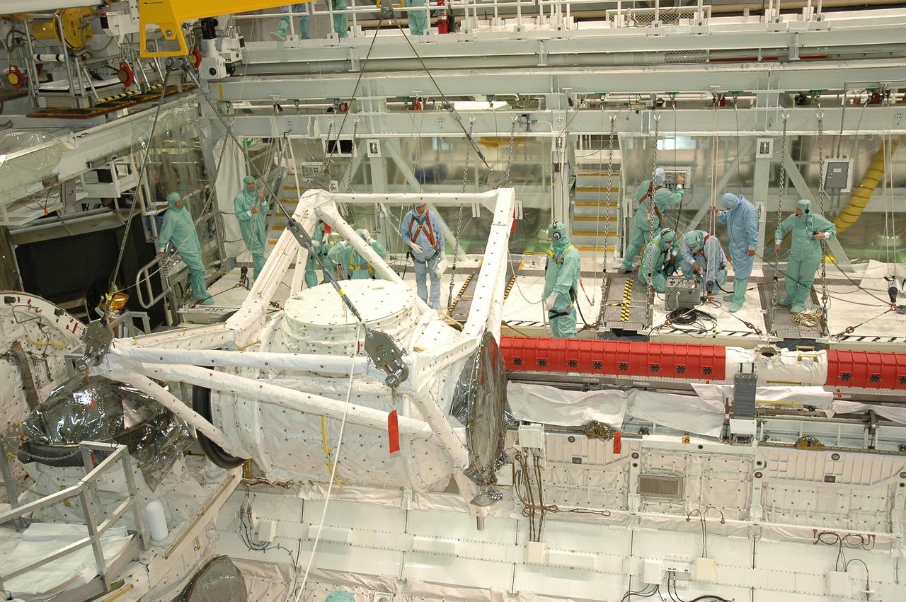 KENNEDY SPACE CENTER, FLA. -- In Orbiter Processing Facility bay 2 at NASA's Kennedy Space Center, the crew airlock module is lowered into place in Endeavour's payload bay, where it will be installed. The airlock is located in the middeck. The airlock and airlock hatches permit flight crew members to transfer from the middeck crew compartment into the payload bay for extravehicular activities in their space suits without depressurizing the orbiter crew cabin. The airlock is sized to accommodate two fully suited flight crew members simultaneously. Endeavour is targeted for flight on Aug. 9 on mission STS-118 to the International Space Station. Photo credit: NASA/Jack Pfaller