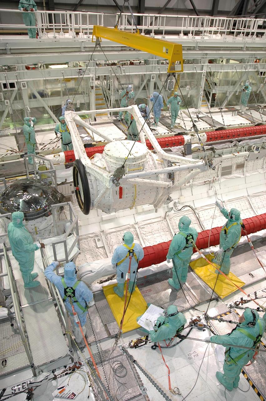 KENNEDY SPACE CENTER, FLA. -- In Orbiter Processing Facility bay 2 at NASA's Kennedy Space Center, technicians control the descent of the crew airlock module into Endeavour's payload bay, where it will be installed. The airlock is located in the middeck. The airlock and airlock hatches permit flight crew members to transfer from the middeck crew compartment into the payload bay for extravehicular activities in their space suits without depressurizing the orbiter crew cabin. The airlock is sized to accommodate two fully suited flight crew members simultaneously. Endeavour is targeted for flight on Aug. 9 on mission STS-118 to the International Space Station. Photo credit: NASA/Jack Pfaller