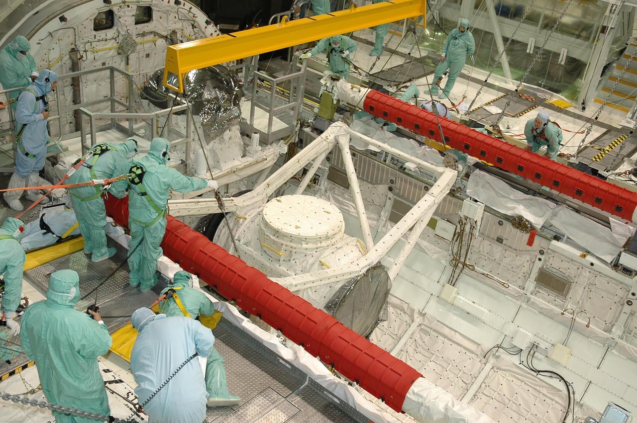 KENNEDY SPACE CENTER, FLA. -- In Orbiter Processing Facility bay 2 at NASA's Kennedy Space Center, technicians direct the placement of the crew airlock module into Endeavour's payload bay, where it will be installed. The airlock is located in the middeck. The airlock and airlock hatches permit flight crew members to transfer from the middeck crew compartment into the payload bay for extravehicular activities in their space suits without depressurizing the orbiter crew cabin. The airlock is sized to accommodate two fully suited flight crew members simultaneously. Endeavour is targeted for flight on Aug. 9 on mission STS-118 to the International Space Station. Photo credit: NASA/Jack Pfaller