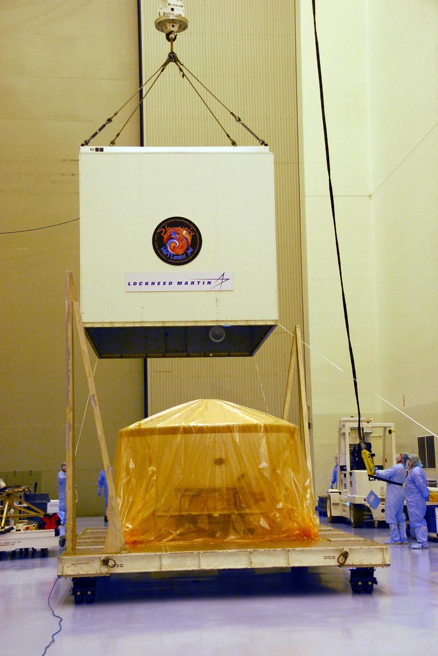 KENNEDY SPACE CENTER, FLA. --  In the Payload Hazardous Servicing Facility at Kennedy Space Center, a crane lifts the shipping crate from around the Phoenix spacecraft.  The spacecraft arrived May 7 via a U.S. Air Force C-17 Globemaster III at the Shuttle Landing Facility. The Phoenix mission is the first project in NASA's first openly competed program of Mars Scout missions. Phoenix will land in icy soils near the north polar permanent ice cap of Mars and explore the history of the water in these soils and any associated rocks, while monitoring polar climate. Landing is planned in May 2008 on arctic ground where a mission currently in orbit, Mars Odyssey, has detected high concentrations of ice just beneath the top layer of soil. It will serve as NASA's first exploration of a potential modern habitat on Mars and open the door to a renewed search for carbon-bearing compounds, last attempted with NASA’s Viking missions in the 1970s. A stereo color camera and a weather station will study the surrounding environment while the other instruments check excavated soil samples for water, organic chemicals and conditions that could indicate whether the site was ever hospitable to life. Microscopes can reveal features as small as one one-thousandth the width of a human hair. Launch of Phoenix aboard a Delta II rocket is targeted for Aug. 3 from Cape Canaveral Air Force Station in Florida.  Photo credit: NASA/George Shelton