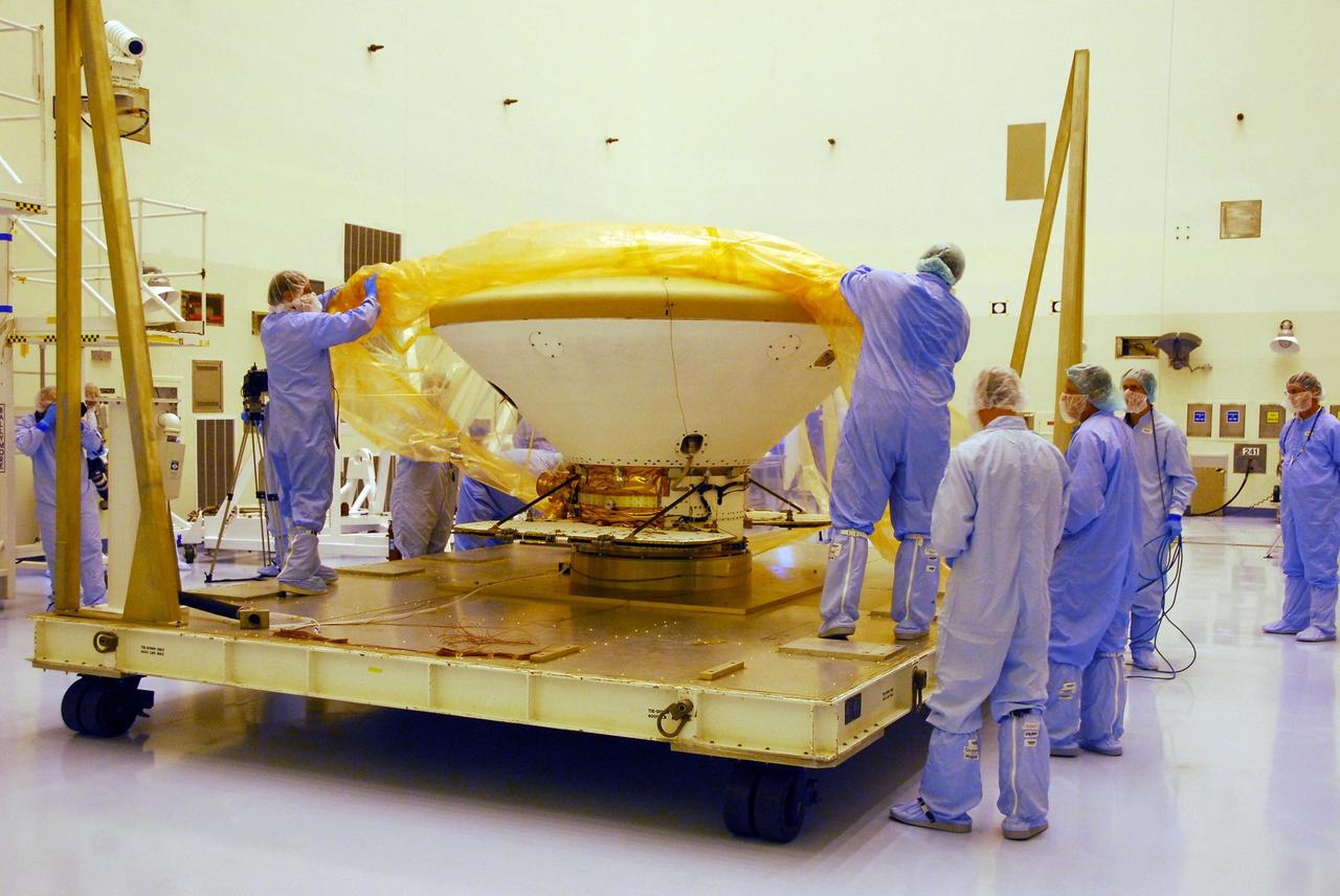 KENNEDY SPACE CENTER, FLA. --  In the Payload Hazardous Servicing Facility at Kennedy Space Center, workers dressed in clean-room garb remove the protective wrapping from around the Phoenix spacecraft. The Phoenix mission is the first project in NASA's first openly competed program of Mars Scout missions. Phoenix will land in icy soils near the north polar permanent ice cap of Mars and explore the history of the water in these soils and any associated rocks, while monitoring polar climate. Landing is planned in May 2008 on arctic ground where a mission currently in orbit, Mars Odyssey, has detected high concentrations of ice just beneath the top layer of soil. It will serve as NASA's first exploration of a potential modern habitat on Mars and open the door to a renewed search for carbon-bearing compounds, last attempted with NASA’s Viking missions in the 1970s. A stereo color camera and a weather station will study the surrounding environment while the other instruments check excavated soil samples for water, organic chemicals and conditions that could indicate whether the site was ever hospitable to life. Microscopes can reveal features as small as one one-thousandth the width of a human hair. Launch of Phoenix aboard a Delta II rocket is targeted for Aug. 3 from Cape Canaveral Air Force Station in Florida.  Photo credit: NASA/George Shelton