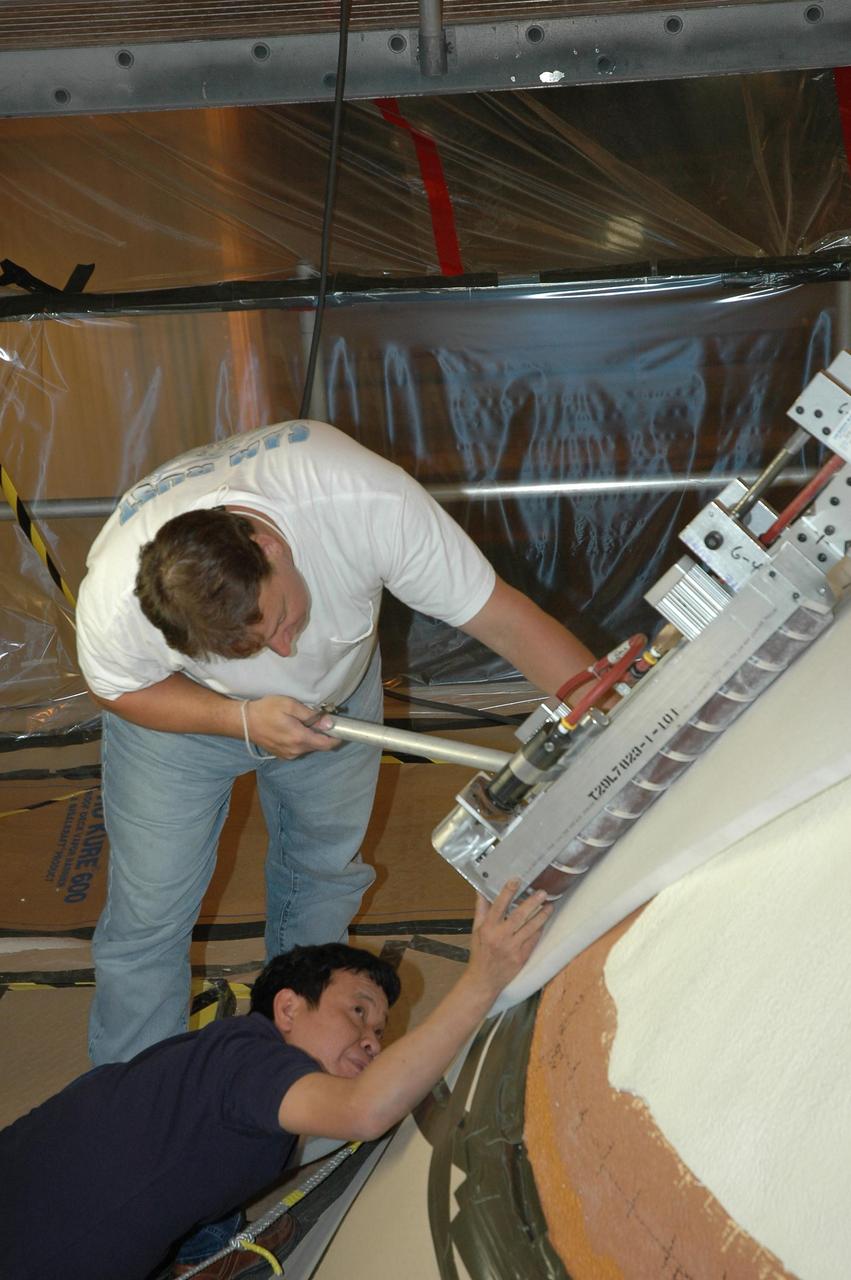 KENNEDY SPACE CENTER, FLA. --  In NASA Kennedy Space Center's Vehicle Assembly Building, technicians  place a piece of foam on the side of Atlantis' nose cone to rest the sander while they make adjustments.  In late February, Atlantis' external tank received hail damage during a severe thunderstorm that passed through the Kennedy Space Center Launch Complex 39 area. The hail caused visible divots in the giant tank's foam insulation as well as minor surface damage to about 26 heat shield tiles on the shuttle's left wing.  The launch of Space Shuttle Atlantis on mission STS-117 now is targeted for June 8.  Photo credit: NASA/Jack Pfaller