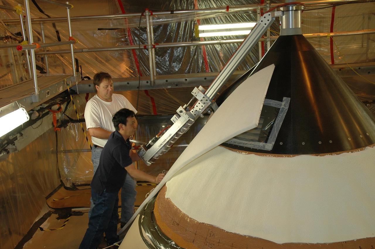 KENNEDY SPACE CENTER, FLA. --  In NASA Kennedy Space Center's Vehicle Assembly Building, one technician adjusts the sander while another observes as they work on repairing the hail damage to Atlantis' nose cone.  In late February, Atlantis' external tank received hail damage during a severe thunderstorm that passed through the Kennedy Space Center Launch Complex 39 area. The hail caused visible divots in the giant tank's foam insulation as well as minor surface damage to about 26 heat shield tiles on the shuttle's left wing.  The launch of Space Shuttle Atlantis on mission STS-117 now is targeted for June 8.  Photo credit: NASA/Jack Pfaller