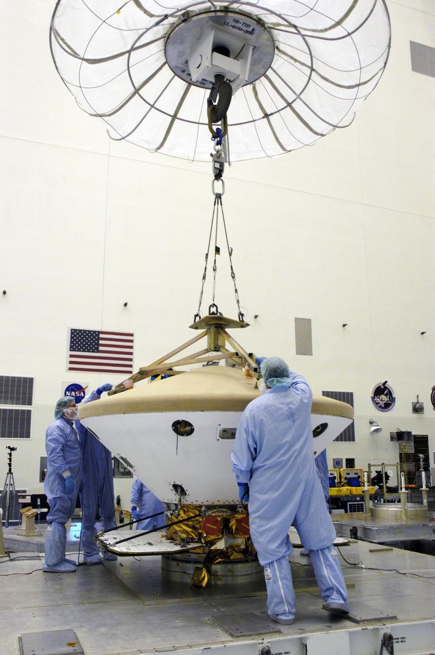 KENNEDY SPACE CENTER, FLA. --  In the Payload Hazardous Servicing Facility, technicians attach a crane to the Phoenix Mars Lander spacecraft.  The crane will be used to remove the heat shield from around the Phoenix.  The Phoenix mission is the first project in NASA's first openly competed program of Mars Scout missions. Phoenix will land in icy soils near the north polar permanent ice cap of Mars and explore the history of the water in these soils and any associated rocks, while monitoring polar climate. Landing is planned in May 2008 on arctic ground where a mission currently in orbit, Mars Odyssey, has detected high concentrations of ice just beneath the top layer of soil. It will serve as NASA's first exploration of a potential modern habitat on Mars and open the door to a renewed search for carbon-bearing compounds, last attempted with NASA’s Viking missions in the 1970s. A stereo color camera and a weather station will study the surrounding environment while the other instruments check excavated soil samples for water, organic chemicals and conditions that could indicate whether the site was ever hospitable to life. Microscopes can reveal features as small as one one-thousandth the width of a human hair. Launch of Phoenix aboard a Delta II rocket is targeted for Aug. 3 from Cape Canaveral Air Force Station in Florida.   Photo credit: NASA/George Shelton