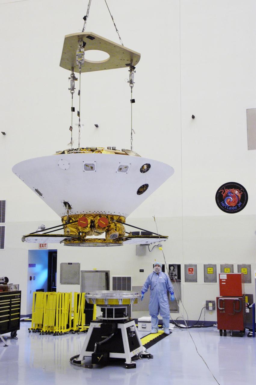 KENNEDY SPACE CENTER, FLA. -- An overhead crane lowers the backshell with the Phoenix Mars Lander inside toward a spin table for spin testing in the Payload Hazardous Servicing Facility. The Phoenix mission is the first project in NASA's first openly competed program of Mars Scout missions. Phoenix will land in icy soils near the north polar permanent ice cap of Mars and explore the history of the water in these soils and any associated rocks, while monitoring polar climate. Landing is planned in May 2008 on arctic ground where a mission currently in orbit, Mars Odyssey, has detected high concentrations of ice just beneath the top layer of soil. It will serve as NASA's first exploration of a potential modern habitat on Mars and open the door to a renewed search for carbon-bearing compounds, last attempted with NASA’s Viking missions in the 1970s. A stereo color camera and a weather station will study the surrounding environment while the other instruments check excavated soil samples for water, organic chemicals and conditions that could indicate whether the site was ever hospitable to life. Microscopes can reveal features as small as one one-thousandth the width of a human hair. Launch of Phoenix aboard a Delta II rocket is targeted for Aug. 3 from Cape Canaveral Air Force Station in Florida.   Photo credit: NASA/George Shelton