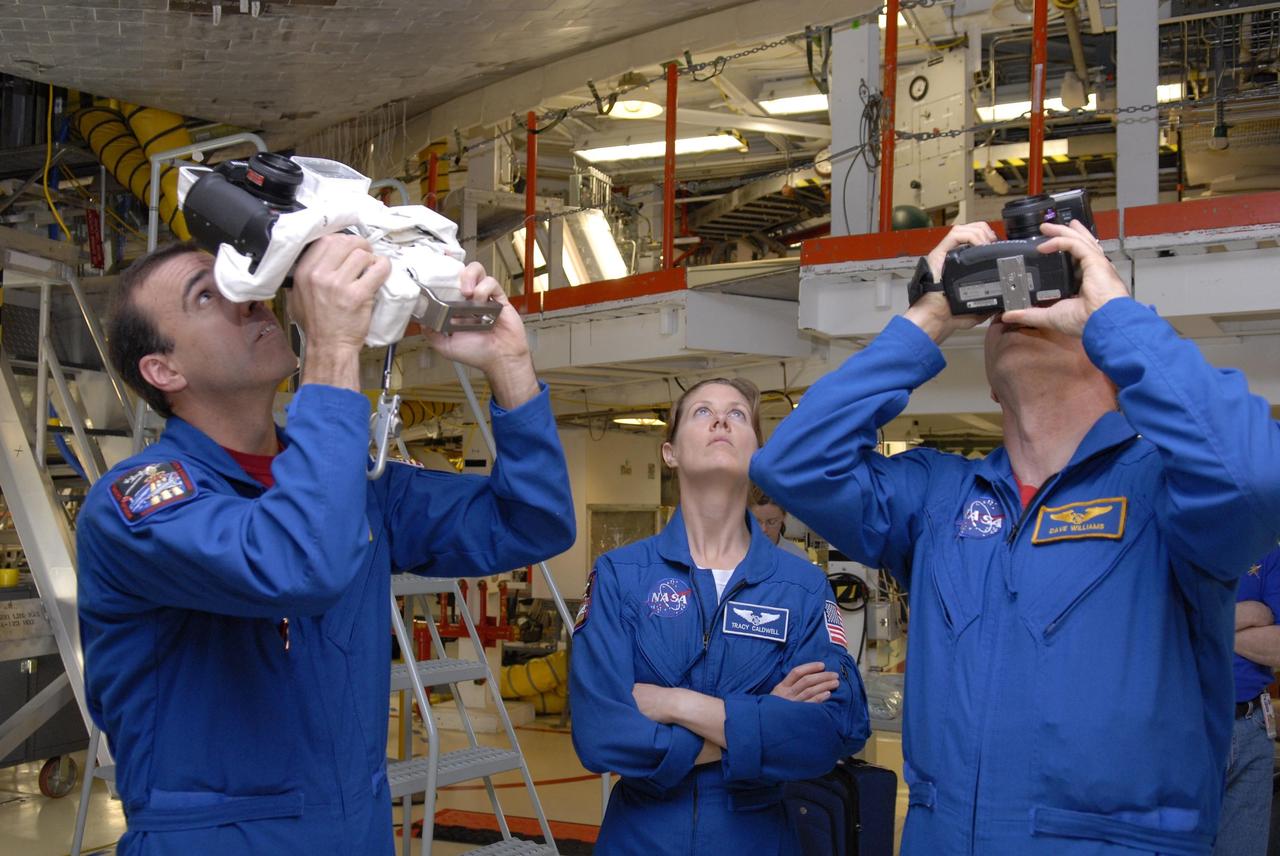 KENNEDY SPACE CENTER, FLA. --  In Orbiter Processing Facility bay 2, during crew equipment interface test activities, STS-118 Mission Specialists Dr. Dafydd Williams (left) and Richard Mastrocchio (right) practice photographing the underside of the orbiter Endeavour, which they may do on the flight.  At center is Mission Specialist Tracy Caldwell, who will also practice with the cameras. The STS-118 mission will be delivering the third starboard truss segment, the ITS S5, to the International Space Station, as well as the SPACEHAB single cargo module filled with supplies and equipment.  Launch aboard Space Shuttle Endeavour is targeted for Aug. 9.   Photo credit: NASA/Kim Shiflett