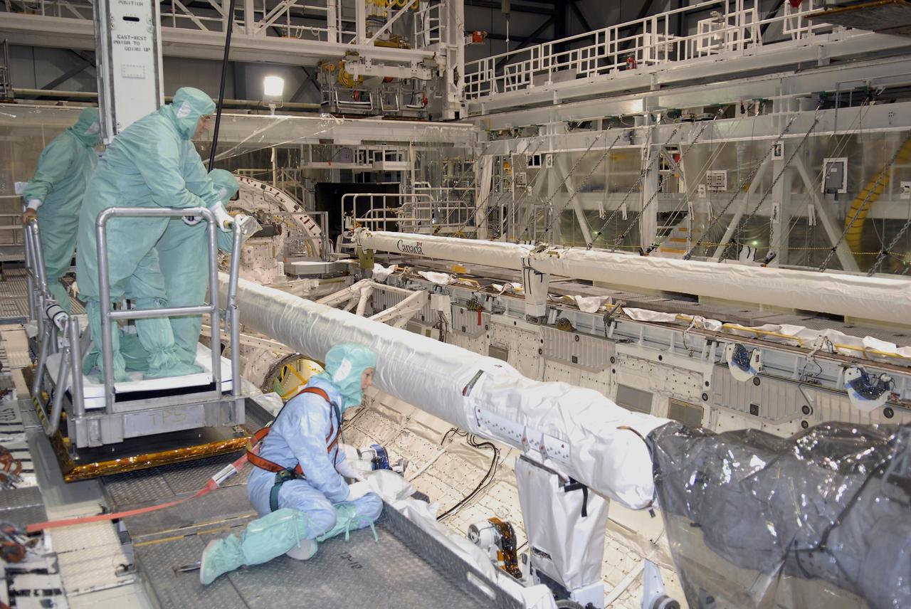 KENNEDY SPACE CENTER, FLA. --    During crew equipment interface test activities at KSC, STS-118 Mission Specialists Dr. Dafydd Williams (standing in the lift) and Tracy Caldwell (seated at right) look over the shuttle arm in Endeavour's payload bay. The STS-118 mission will be delivering the third starboard truss segment, the ITS S5, to the International Space Station, as well as the SPACEHAB single cargo module filled with supplies and equipment.  Launch aboard Space Shuttle Endeavour is targeted for Aug. 9.   Photo credit: NASA/Kim Shiflett