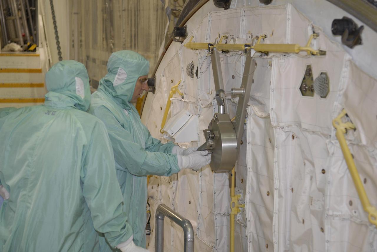 KENNEDY SPACE CENTER, FLA. -- During crew equipment interface test activities at KSC, STS-118 Mission Specialist Dr. Dafydd Williams (right) maneuvers the latch on the crew airlock module. The airlock is located in the middeck. The airlock and airlock hatches permit flight crew members to transfer from the middeck crew compartment into the payload bay for extravehicular activities in their space suits without depressurizing the orbiter crew cabin. The airlock is sized to accommodate two fully suited flight crew members simultaneously. The STS-118 mission will be delivering the third starboard truss segment, the ITS S5, to the International Space Station, as well as the SPACEHAB single cargo module filled with supplies and equipment. Launch aboard Space Shuttle Endeavour is targeted for Aug. 9. Photo credit: NASA/Kim Shiflett