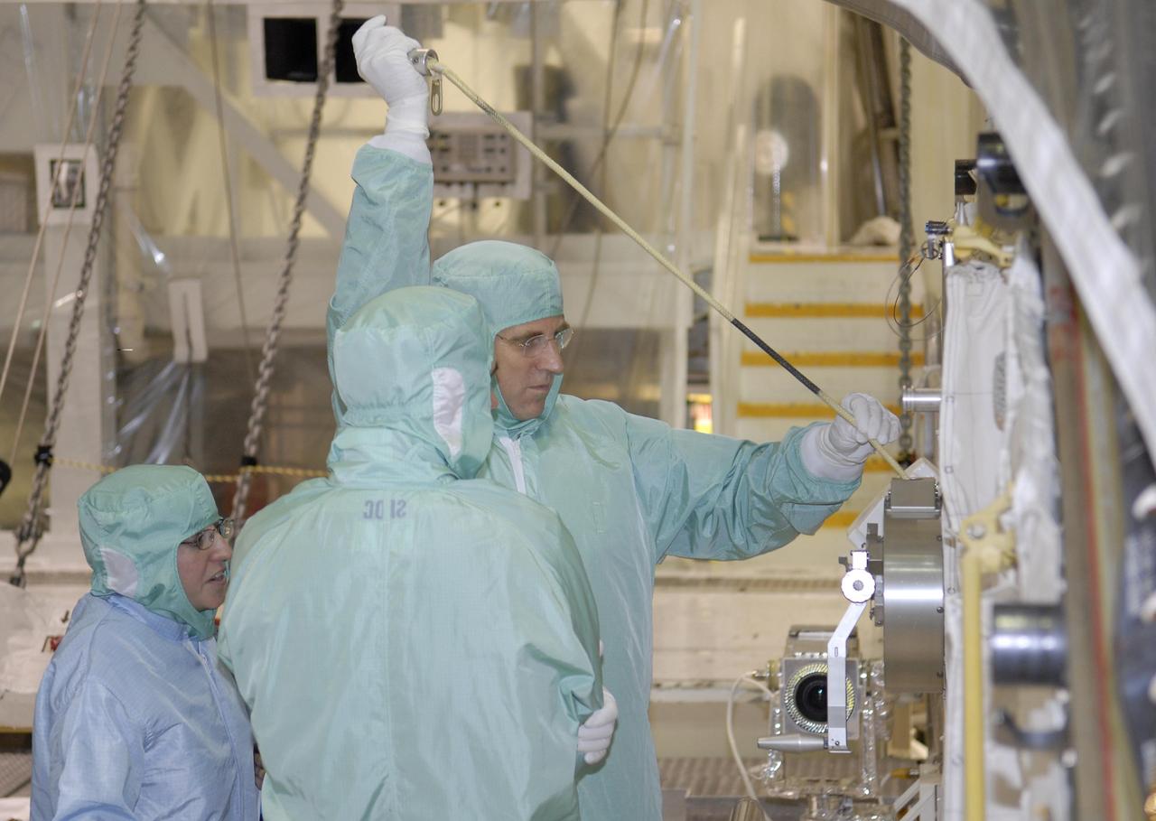 KENNEDY SPACE CENTER, FLA. -- During crew equipment interface test activities at KSC, STS-118 Mission Specialist Dr. Dafydd Williams (right) maneuvers the latch on the crew airlock module. The airlock is located in the middeck. The airlock and airlock hatches permit flight crew members to transfer from the middeck crew compartment into the payload bay for extravehicular activities in their space suits without depressurizing the orbiter crew cabin. The airlock is sized to accommodate two fully suited flight crew members simultaneously. The STS-118 mission will be delivering the third starboard truss segment, the ITS S5, to the International Space Station, as well as the SPACEHAB single cargo module filled with supplies and equipment. Launch aboard Space Shuttle Endeavour is targeted for Aug. 9. Photo credit: NASA/Kim Shiflett