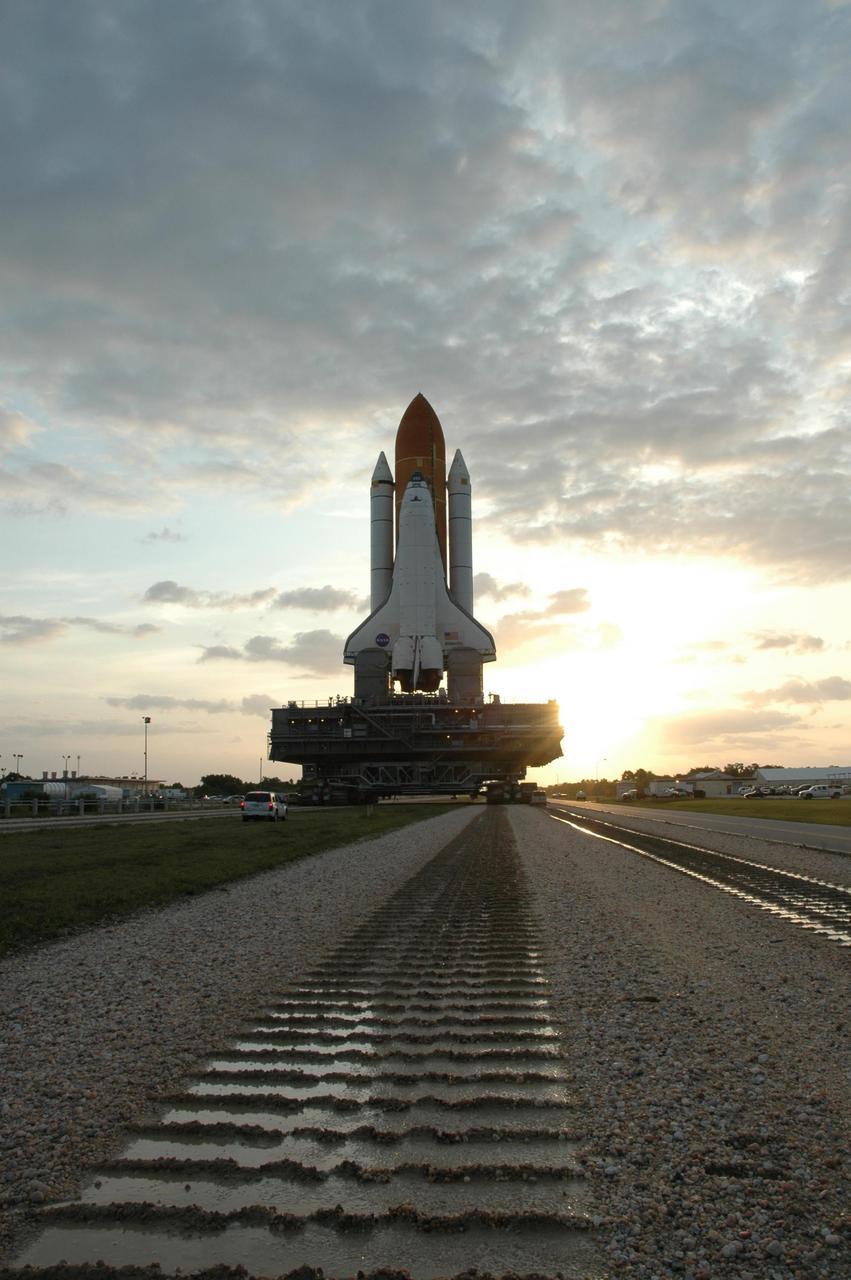 KENNEDY SPACE CENTER, FLA. --  Just after sunrise, Space Shuttle Atlantis, mounted on a mobile launch platform, rolls a second time to Launch Pad 39A atop a crawler transporter.  First motion out of the Vehicle Assembly Building was at 5:02 a.m. EDT. In late February, while Atlantis was on the launch pad, Atlantis' external tank received hail damage during a severe thunderstorm that passed through the Kennedy Space Center Launch Complex 39 area. The hail caused visible divots in the giant tank's foam insulation, as well as minor surface damage to about 26 heat shield tiles on the shuttle's left wing. The shuttle was returned to the VAB for repairs. The launch of Space Shuttle Atlantis on mission STS-117 is now targeted for June 8. A flight readiness review will be held on May 30 and 31. Photo credit: NASA/Jim Grossmann