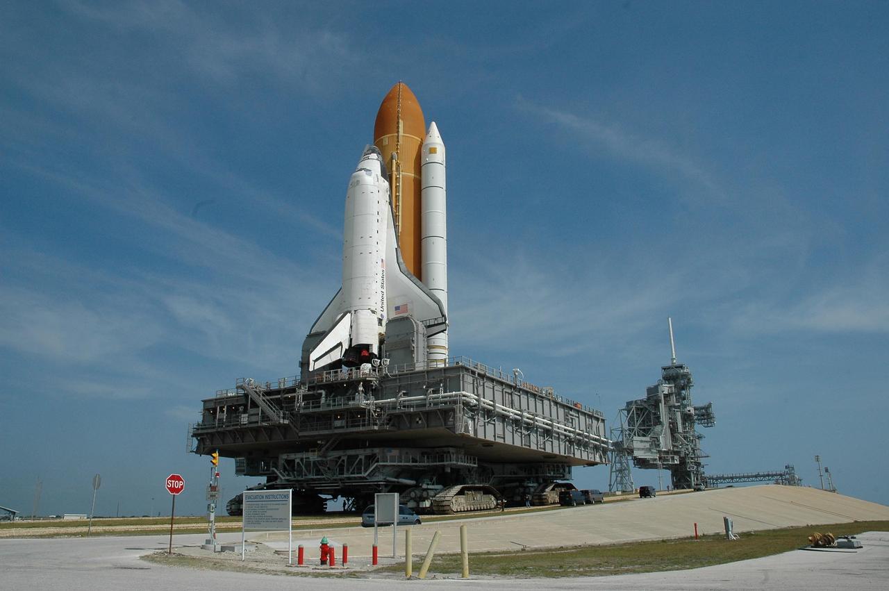 KENNEDY SPACE CENTER, FLA. --  Under a feather-painted sky, Space Shuttle Atlantis, mounted on a mobile launch platform atop a crawler transporter, creeps up the ramp to Launch Pad 39A.  This is the second rollout for the shuttle.  First motion out of the Vehicle Assembly Building was at 5:02 a.m. EDT. In late February, while Atlantis was on the launch pad, Atlantis' external tank received hail damage during a severe thunderstorm that passed through the Kennedy Space Center Launch Complex 39 area. The hail caused visible divots in the giant tank's foam insulation, as well as minor surface damage to about 26 heat shield tiles on the shuttle's left wing. The shuttle was returned to the VAB for repairs. The launch of Space Shuttle Atlantis on mission STS-117 is now targeted for June 8. A flight readiness review will be held on May 30 and 31.  Photo credit: NASA/Troy Cryder