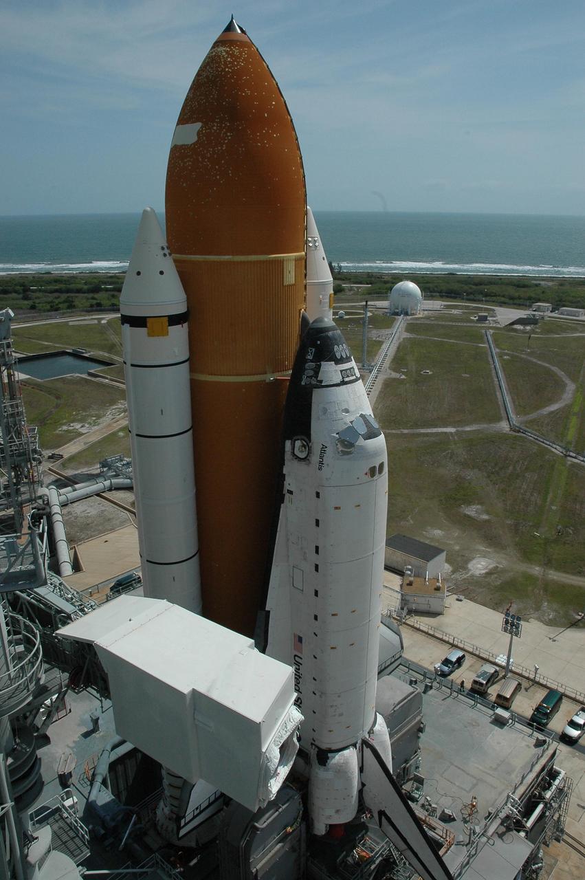 KENNEDY SPACE CENTER, FLA. --    Space Shuttle Atlantis, mounted on a mobile launch platform, finally rests on the hard stand of Launch Pad 39A.   At bottom left is the White Room, which is situated on the end of the fixed service structure's orbiter access arm.  At the top of the photo, in the background, is the Atlantic Ocean.   This is the second rollout for the shuttle.  First motion out of the Vehicle Assembly Building was at 5:02 a.m. EDT. In late February, while Atlantis was on the launch pad, Atlantis' external tank received hail damage during a severe thunderstorm that passed through the Kennedy Space Center Launch Complex 39 area. The hail caused visible divots in the giant tank's foam insulation, as well as minor surface damage to about 26 heat shield tiles on the shuttle's left wing. The shuttle was returned to the VAB for repairs. The launch of Space Shuttle Atlantis on mission STS-117 is now targeted for June 8. A flight readiness review will be held on May 30 and 31.  Photo credit: NASA/Troy Cryder