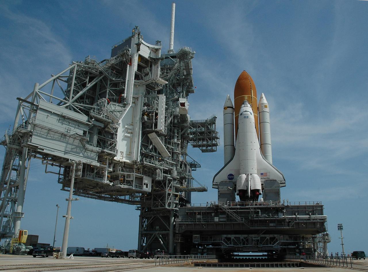 KENNEDY SPACE CENTER, FLA. --   Space Shuttle Atlantis, mounted on a mobile launch platform, finally rests on the hard stand of Launch Pad 39A, straddling the flame trench. This is the second rollout for the shuttle.  The flame trench transecting the pad's mound at ground level is 490 feet long, 58 feet wide and 40 feet high. It is made of concrete and refractory brick. Pad structures are insulated from the intense heat of launch by the flame deflector system, which protects the flame trench floor and the pad surface along the top of the flame trench.  On the left of the shuttle are the fixed service structure and rotating service structure in open position.  When closed, the rotating structure provides protected access to the orbiter for changeout and servicing of payloads at the pad. It is supported by a rotating bridge that pivots about a vertical axis on the west side of the pad's flame trench.  The white area in the center is the Payload Changeout Room, an enclosed, environmentally controlled portion of the rotating service structure that supports payload delivery at the launch pad and subsequent vertical installation in the orbiter payload bay.  First motion out of the Vehicle Assembly Building was at 5:02 a.m. EDT. In late February, while Atlantis was on the launch pad, Atlantis' external tank received hail damage during a severe thunderstorm that passed through the Kennedy Space Center Launch Complex 39 area. The hail caused visible divots in the giant tank's foam insulation, as well as minor surface damage to about 26 heat shield tiles on the shuttle's left wing. The shuttle was returned to the VAB for repairs. The launch of Space Shuttle Atlantis on mission STS-117 is now targeted for June 8. A flight readiness review will be held on May 30 and 31.  Photo credit: NASA/Troy Cryder
