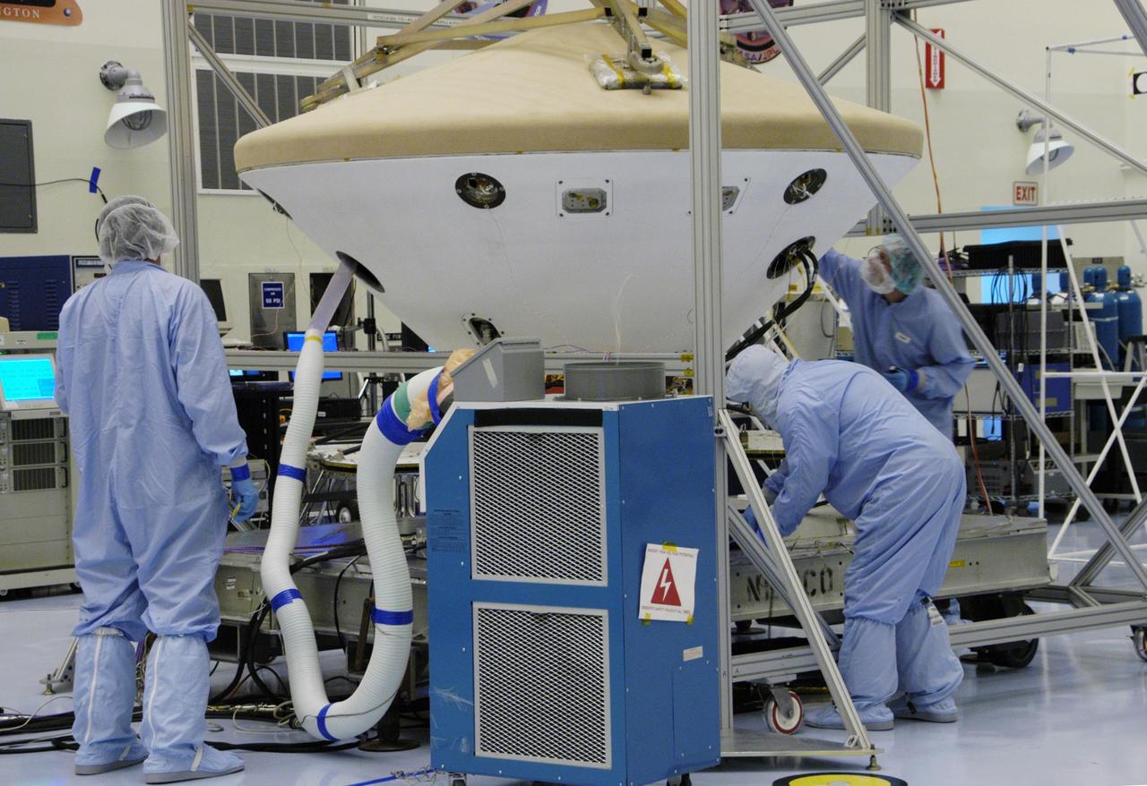KENNEDY SPACE CENTER, FLA. -- In the Payload Hazardous Servicing Facility, workers monitor the Phoenix spacecraft during a heat shield deployment test, with a firing of ordnance associated with the separation device. Phoenix will land in icy soils near the north polar permanent ice cap of Mars and explore the history of the water in these soils and any associated rocks, while monitoring polar climate. Landing is planned in May 2008 on arctic ground where a mission currently in orbit, Mars Odyssey, has detected high concentrations of ice just beneath the top layer of soil. Launch of Phoenix aboard a Delta II rocket is targeted for Aug. 3 from Cape Canaveral Air Force Station in Florida. Photo credit: NASA/George Shelton