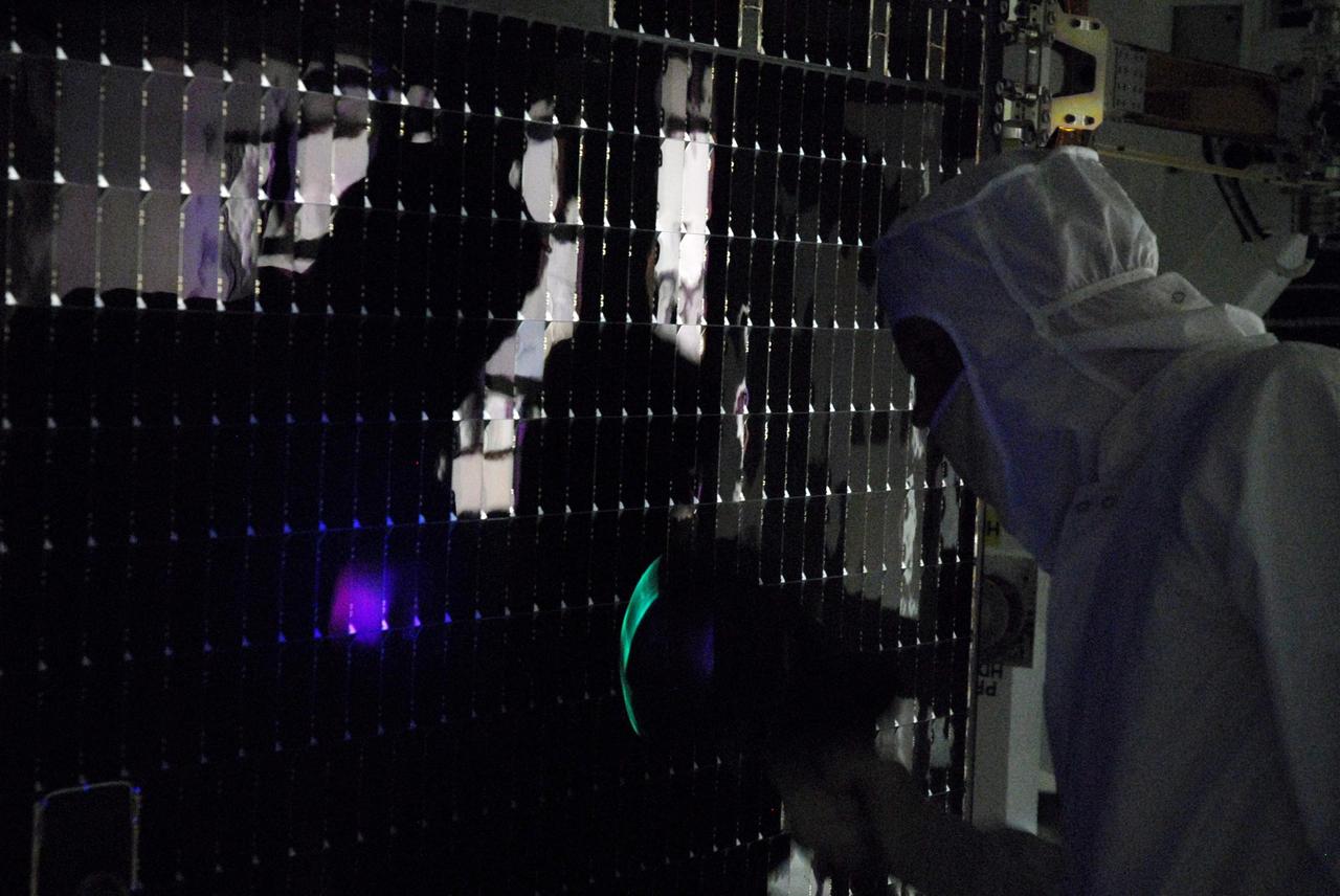 KENNEDY SPACE CENTER, FLA. --  In a clean room at Astrotech, workers begin black light testing on the solar panels of the Dawn spacecraft.  Dawn's mission is to explore two of the asteroid belt's most intriguing and dissimilar occupants: asteroid Vesta and the dwarf planet Ceres.  Dawn is scheduled to launch June 30 from Launch Complex 17-B.  Photo credit: NASA/George Shelton