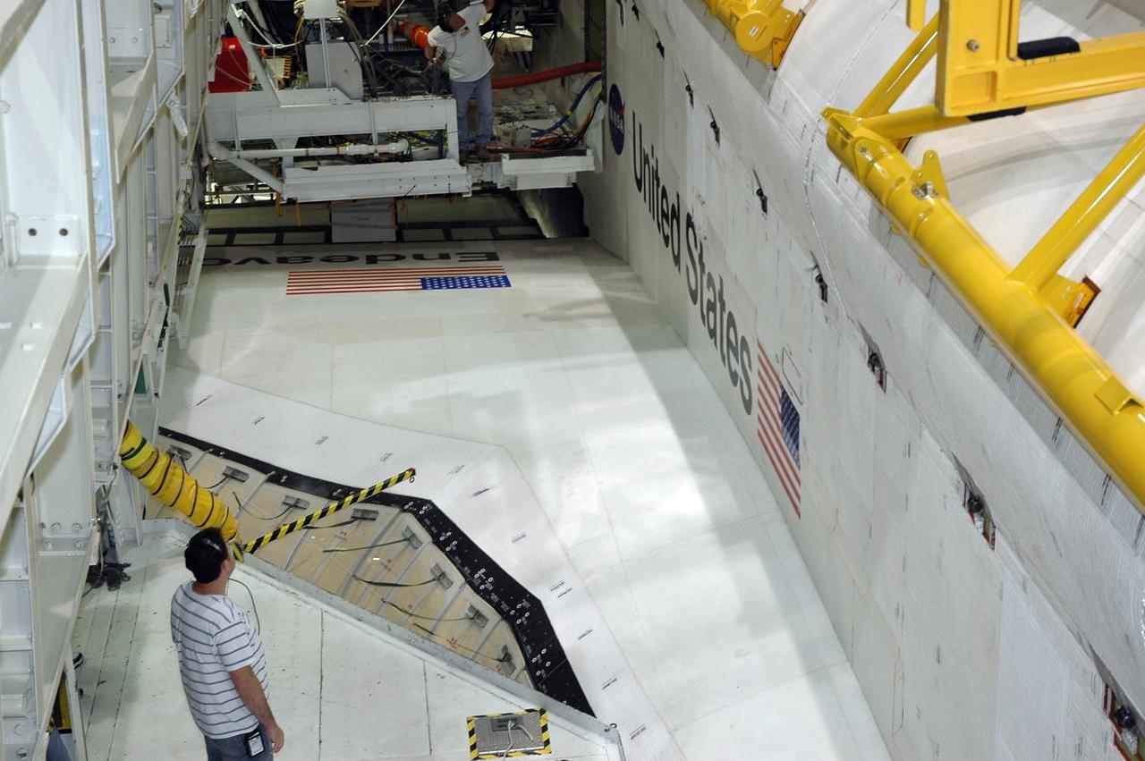 KENNEDY SPACE CENTER, FLA. -- In the Orbiter Processing Facility bay 2, workers are on the wing of Endeavour, checking the progress as the payload bay doors close. The payload will be installed on the launch pad after rollout. The orbiter is designated for mission STS-118, targeted for launch on Aug. 9. The mission will continue space station construction by delivering a third starboard truss segment, S5, as well as carrying the External Stowage Platform 3. The crew comprises seven astronauts: Commander Scott Kelly, Pilot Charles Hobaugh and Mission Specialists Dr. Dafydd (Dave) Williams, Barbara Morgan, Richard Mastracchio, Tracy Caldwell and Benjamin Drew. Williams represents the Canadian Space Agency. Photo credit: NASA/Cory Huston