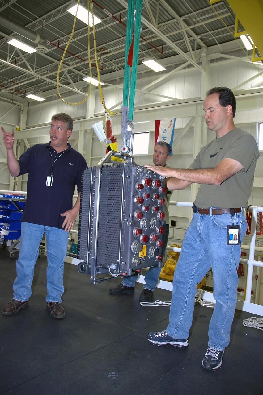 KENNEDY SPACE CENTER, FLA. --   In the Space Shuttle Maine Engine Shop, workers get ready to install an engine controller in one of the three main engines of the orbiter Discovery.  The controller is an electronics package mounted on each space shuttle main engine. It contains two digital computers and the associated electronics to control all main engine components and operations. The controller is attached to the main combustion chamber by shock-mounted fittings.  Discovery is the designated orbiter for mission STS-120 to the International Space Station.  It will carry a payload that includes the Node 2 module, named Harmony. Launch is targeted for no earlier than Oct. 20.   Photo credit: NASA/Cory Huston