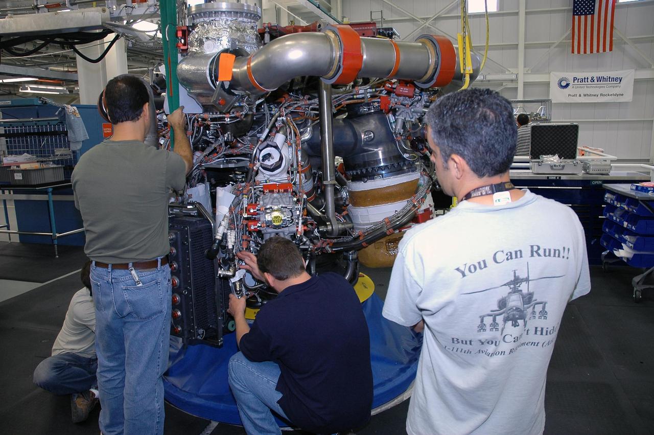 KENNEDY SPACE CENTER, FLA. --  In the Space Shuttle Maine Engine Shop, workers are installing an engine controller in one of the three main engines of the orbiter Discovery. The controller is an electronics package mounted on each space shuttle main engine. It contains two digital computers and the associated electronics to control all main engine components and operations. The controller is attached to the main combustion chamber by shock-mounted fittings.  Discovery is the designated orbiter for mission STS-120 to the International Space Station.  It will carry a payload that includes the Node 2 module, named Harmony. Launch is targeted for no earlier than Oct. 20.   Photo credit: NASA/Cory Huston