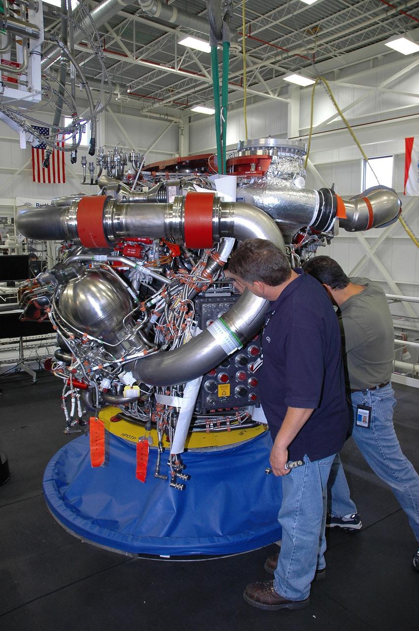 KENNEDY SPACE CENTER, FLA. --   In the Space Shuttle Maine Engine Shop, workers check the installation of an engine controller in one of the three main engines of the orbiter Discovery.  The controller is an electronics package mounted on each space shuttle main engine. It contains two digital computers and the associated electronics to control all main engine components and operations. The controller is attached to the main combustion chamber by shock-mounted fittings.  Discovery is the designated orbiter for mission STS-120 to the International Space Station.  It will carry a payload that includes the Node 2 module, named Harmony. Launch is targeted for no earlier than Oct. 20.   Photo credit: NASA/Cory Huston