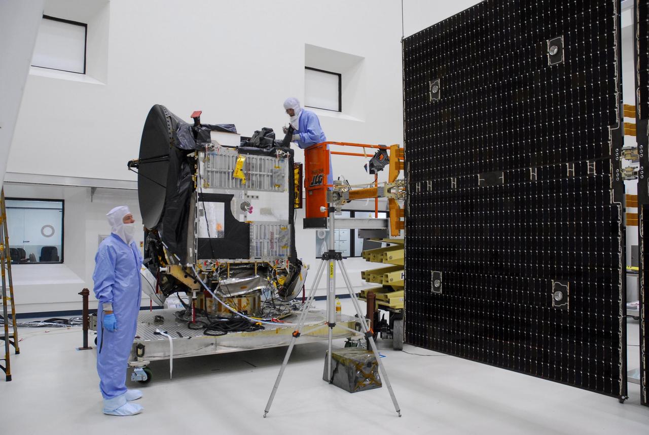 KENNEDY SPACE CENTER, FLA. --  At Astrotech, workers prepare the Dawn spacecraft, at left, for installation of a second set of solar array panels, at right. Together, the panels extend 64.6 feet when fully open.  Dawn is scheduled to launch June 30 aboard a Delta II rocket from Launch Complex 17-B at Cape Canaveral Air Force Station.   Dawn's mission is to explore two of the asteroid belt's most intriguing and dissimilar occupants: asteroid Vesta and the dwarf planet Ceres.  Photo credit: NASA/George Shelton