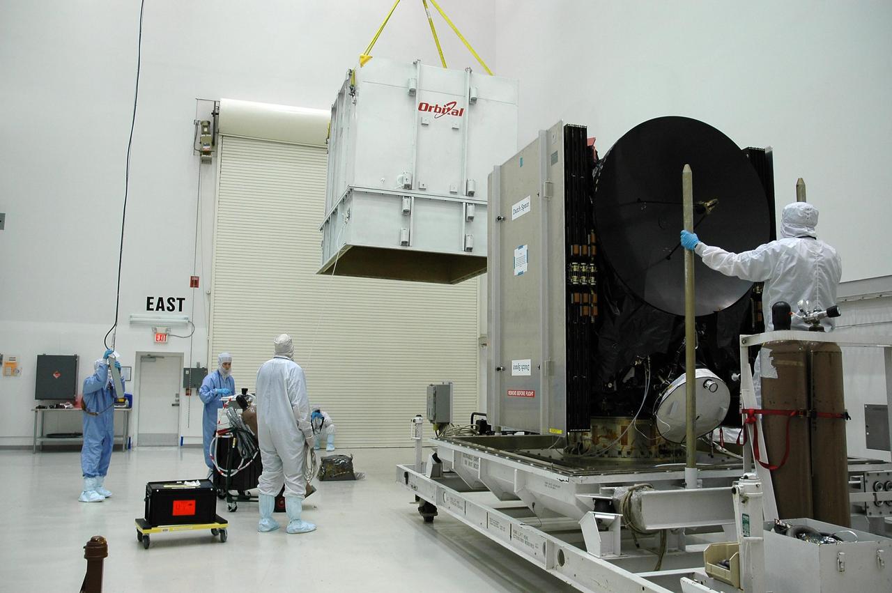 KENNEDY SPACE CENTER, FLA. --At Astrotech's Payload Processing Facility, technicians maneuver the shipping container to place around the Dawn spacecraft, at right.  Dawn will be moved to the Hazardous Processing Facility for fueling. Dawn is scheduled to launch June 30 aboard a Delta II rocket from Launch Complex 17-B at Cape Canaveral Air Force Station.  Dawn's mission is to explore two of the asteroid belt's most intriguing and dissimilar occupants: asteroid Vesta and the dwarf planet Ceres. Photo credit: NASA/Charisse Nahser