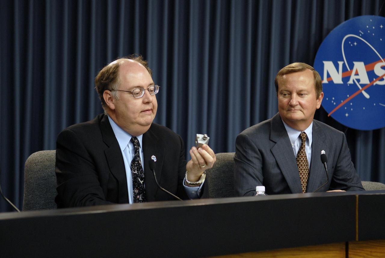 KENNEDY SPACE CENTER, FLA. --  Following the Flight Readiness Review for the STS-117 mission, NASA officials presented the decisions of NASA senior managers in a press conference. Bill Gerstenmaier, associate administrator of NASA Space Operations Mission, confirmed the launch time and date of Space Shuttle Atlantis at 7:38 p.m. EDT on June 8.  Seen here is Space Shuttle Program Manager Wayne Hale (left) demonstrating the level of scrutiny engineers apply to inspecting the smallest of components that make up the shuttle system. This housing and bolt insert are part of the main engine low pressure oxidizer turbopump (LPOTP). NASA Launch Director Mike Leinbach looks on.  Photo credit: NASA/Kim Shiflett