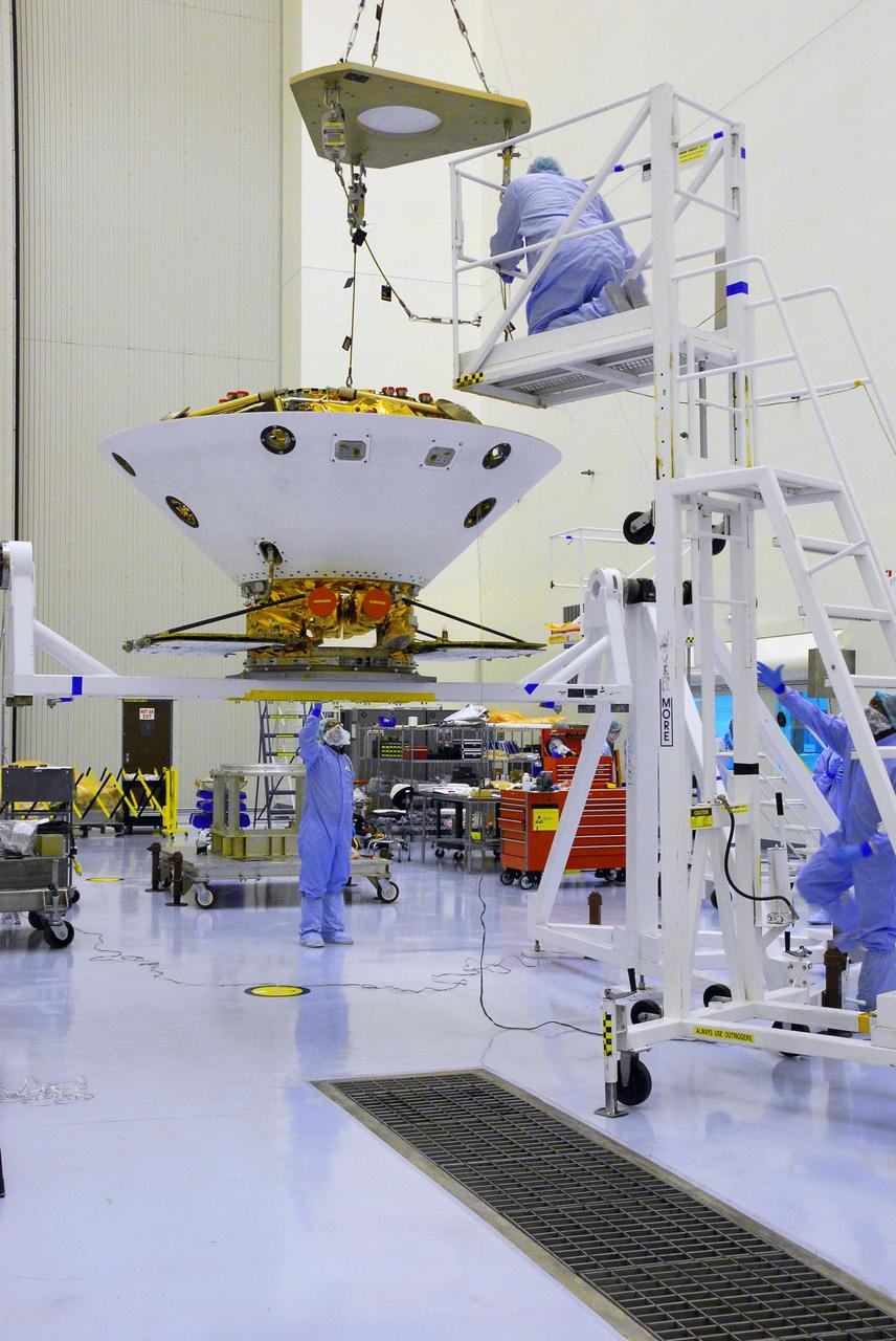 KENNEDY SPACE CENTER, FLA. -- In the Payload Handling Servicing Facility, an overhead crane lowers the Phoenix spacecraft onto a rotation stand for an interim weight and center of gravity determination. The Phoenix mission is the first project in NASA's first openly competed program of Mars Scout missions. Phoenix will land in icy soils near the north polar permanent ice cap of Mars and explore the history of the water in these soils and any associated rocks, while monitoring polar climate. Landing is planned in May 2008 on arctic ground where a mission currently in orbit, Mars Odyssey, has detected high concentrations of ice just beneath the top layer of soil. It will serve as NASA's first exploration of a potential modern habitat on Mars and open the door to a renewed search for carbon-bearing compounds, Photo credit: NASA/George Shelton