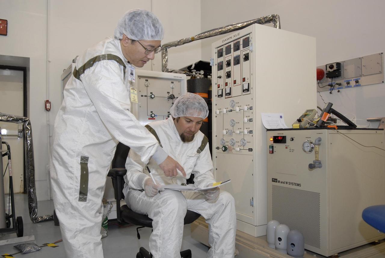 KENNEDY SPACE CENTER, FLA. -- In Astrotech's Hazardous Processing Facility, technicians check data during the loading of xenon for the ion propulsion system in the Dawn spacecraft. Dawn's mission is to explore two of the asteroid belt's most intriguing and dissimilar occupants: asteroid Vesta and the dwarf planet Ceres. The Dawn spacecraft uses ion propulsion to get the additional velocity needed to reach Vesta once it leaves the Delta rocket. It also uses ion propulsion to spiral to lower altitudes on Vesta, to leave Vesta and cruise to Ceres and to spiral to a low-altitude orbit at Ceres. Ion propulsion makes efficient use of the onboard fuel by accelerating it to a velocity 10 times that of chemical rockets. Dawn is scheduled to launch July 7aboard a Delta II rocket from Launch Complex 17-B at Cape Canaveral Air Force Station. Photo credit: NASA/Kim Shiflett